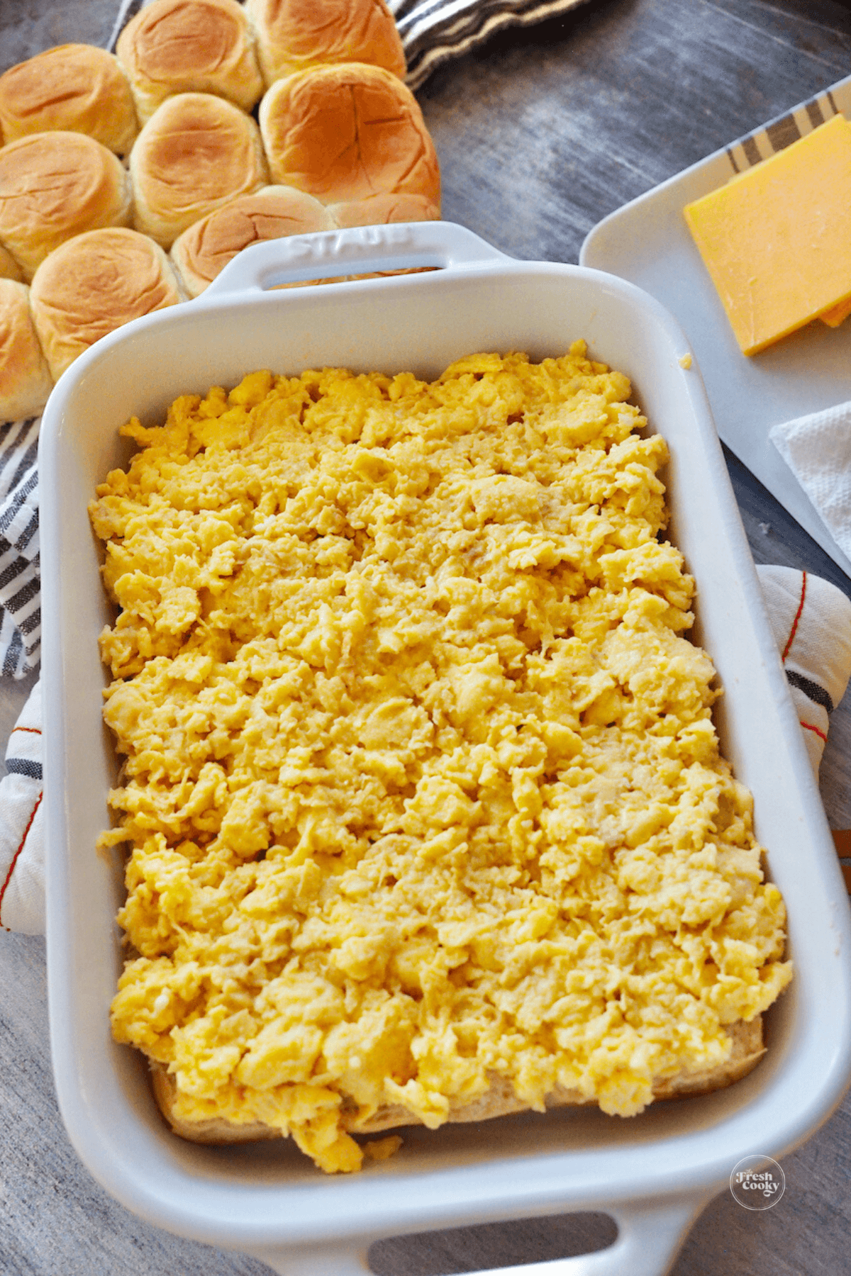 Scrambled eggs spread on top of cheese and rolls. 