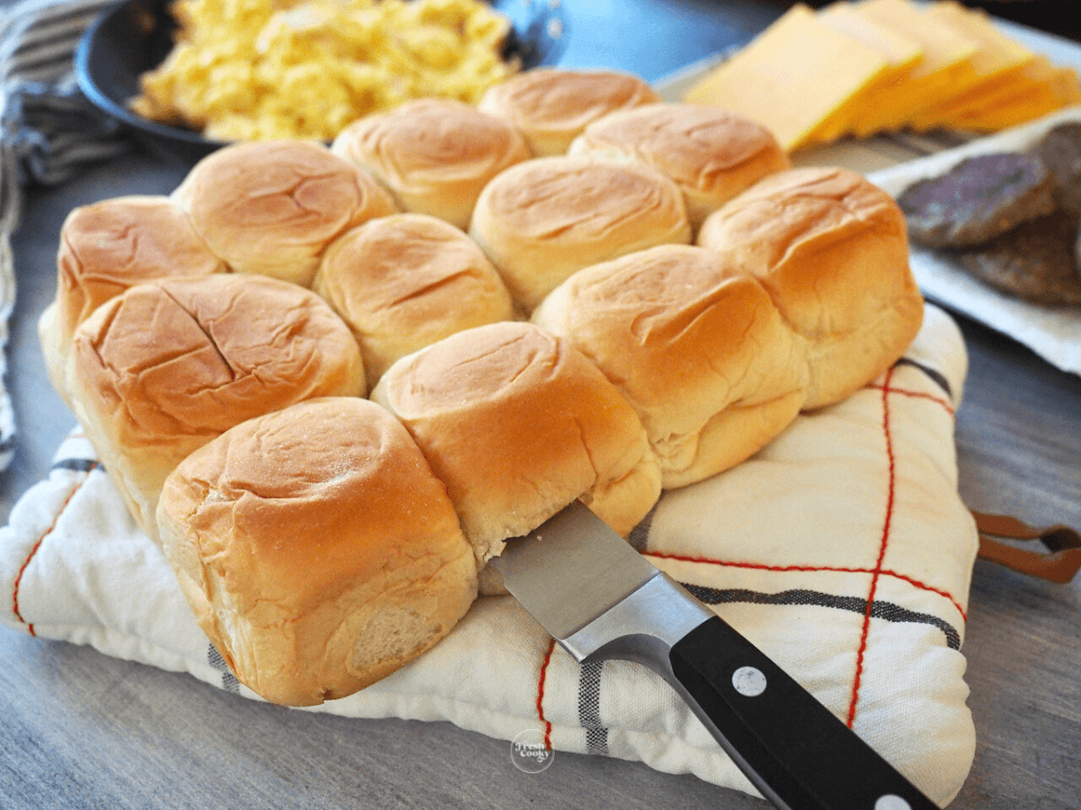 Slicing the hawaiian rolls in half, lengthwise.