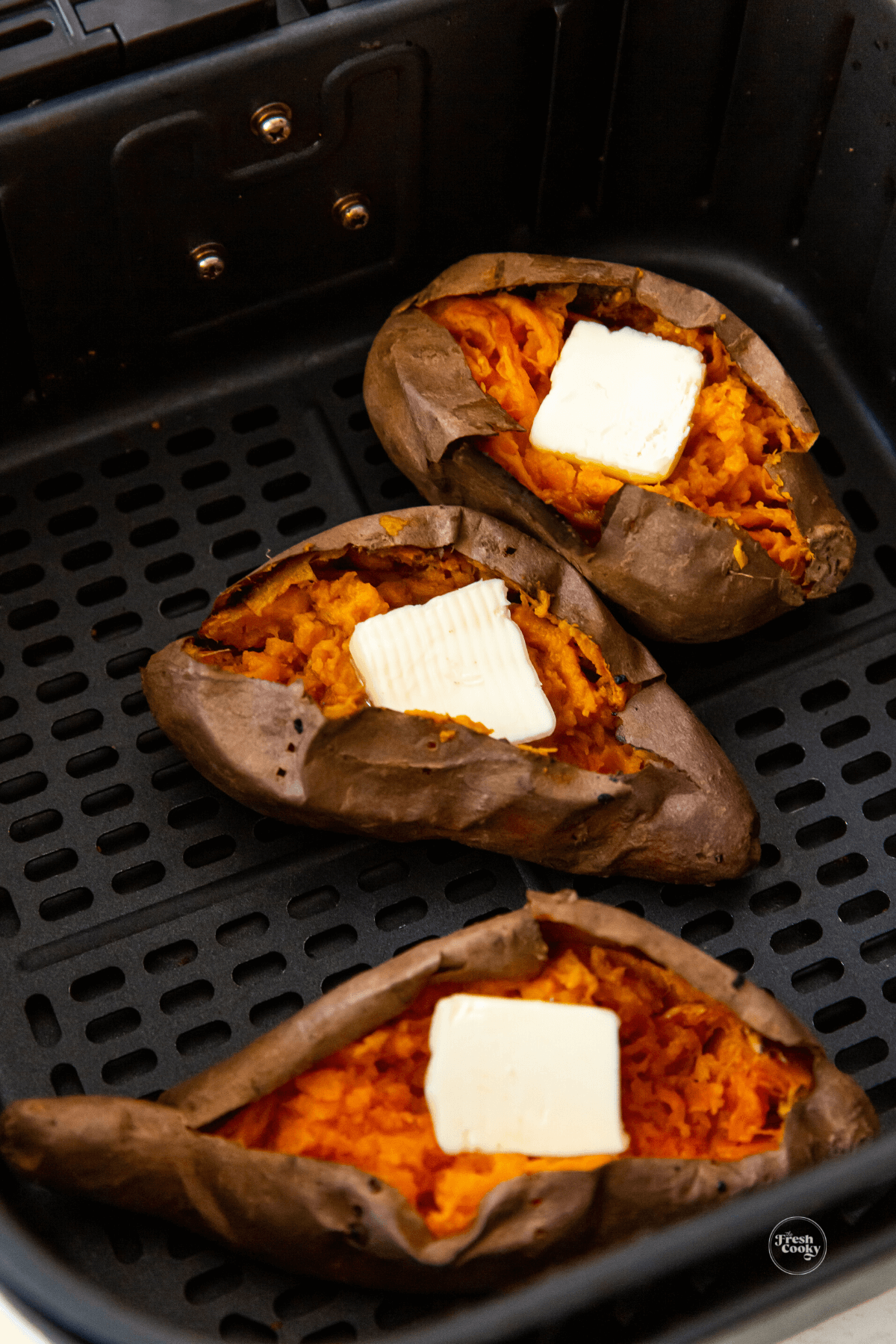 Butter pats on opened air fryer baked sweet potatoes.