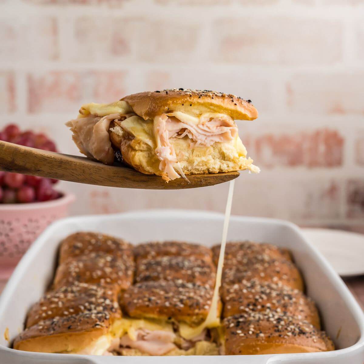 Turkey and cheese slider with gooey cheesy string, being served.