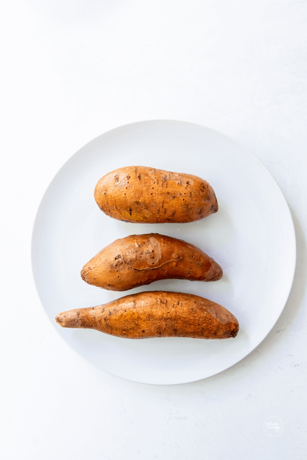 Washed and lightly oiled sweet potatoes on plate. 