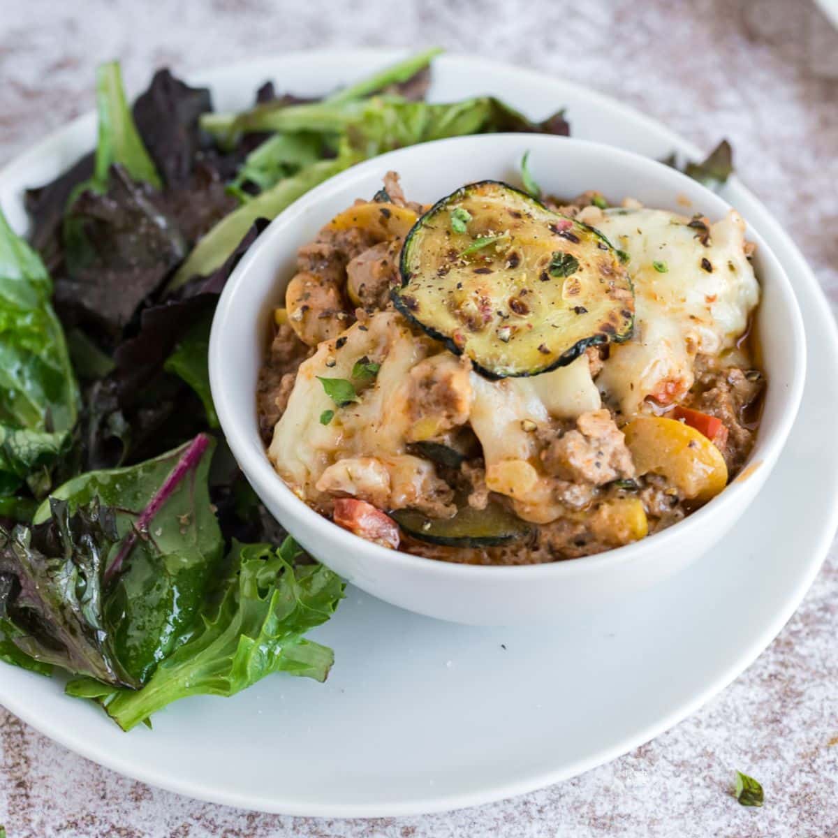 Easy Zucchini and ground beef casserole in bowl with fresh salad.