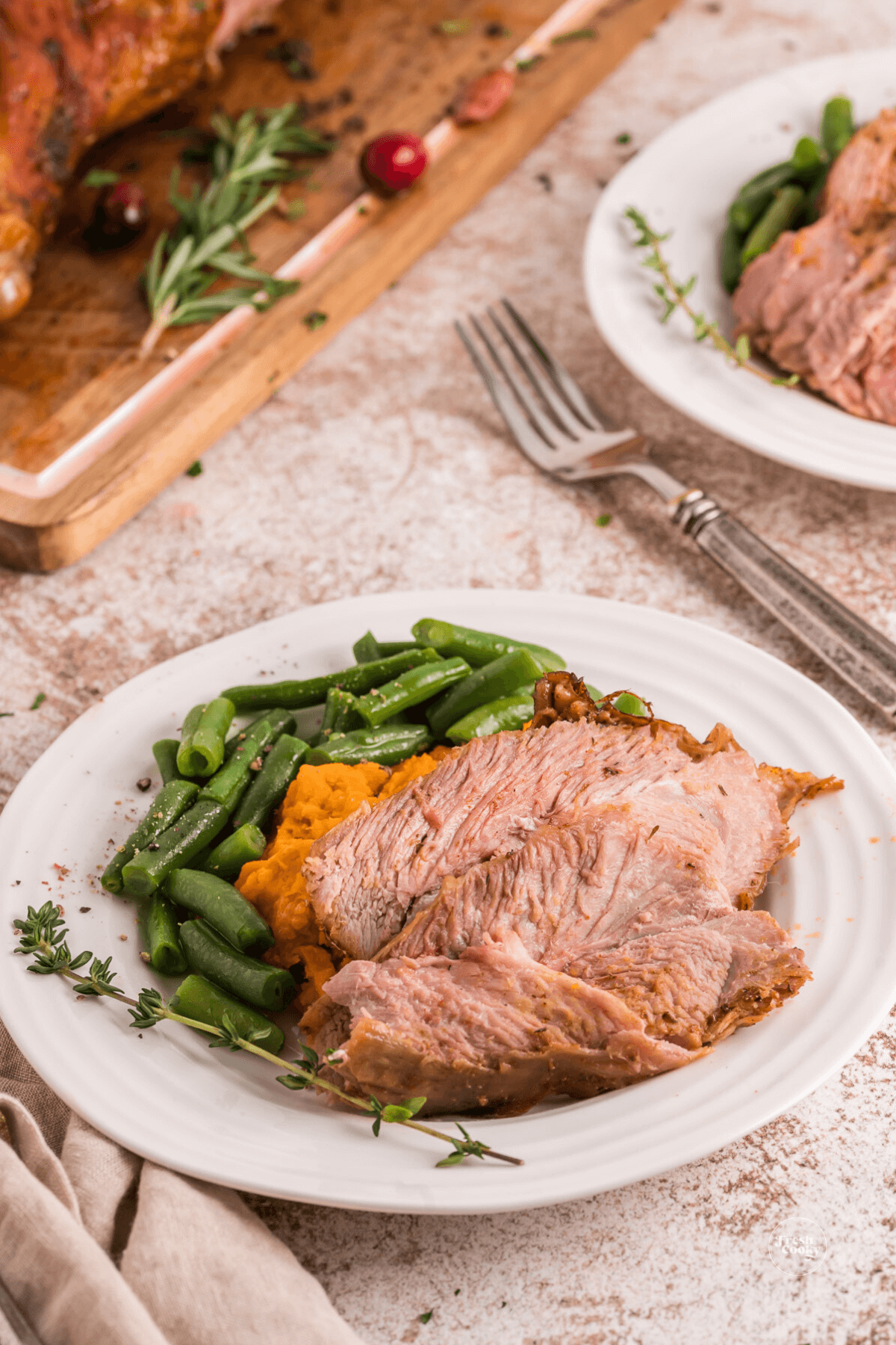Plates of turkey leg meat and green beans with sweet potatoes.
