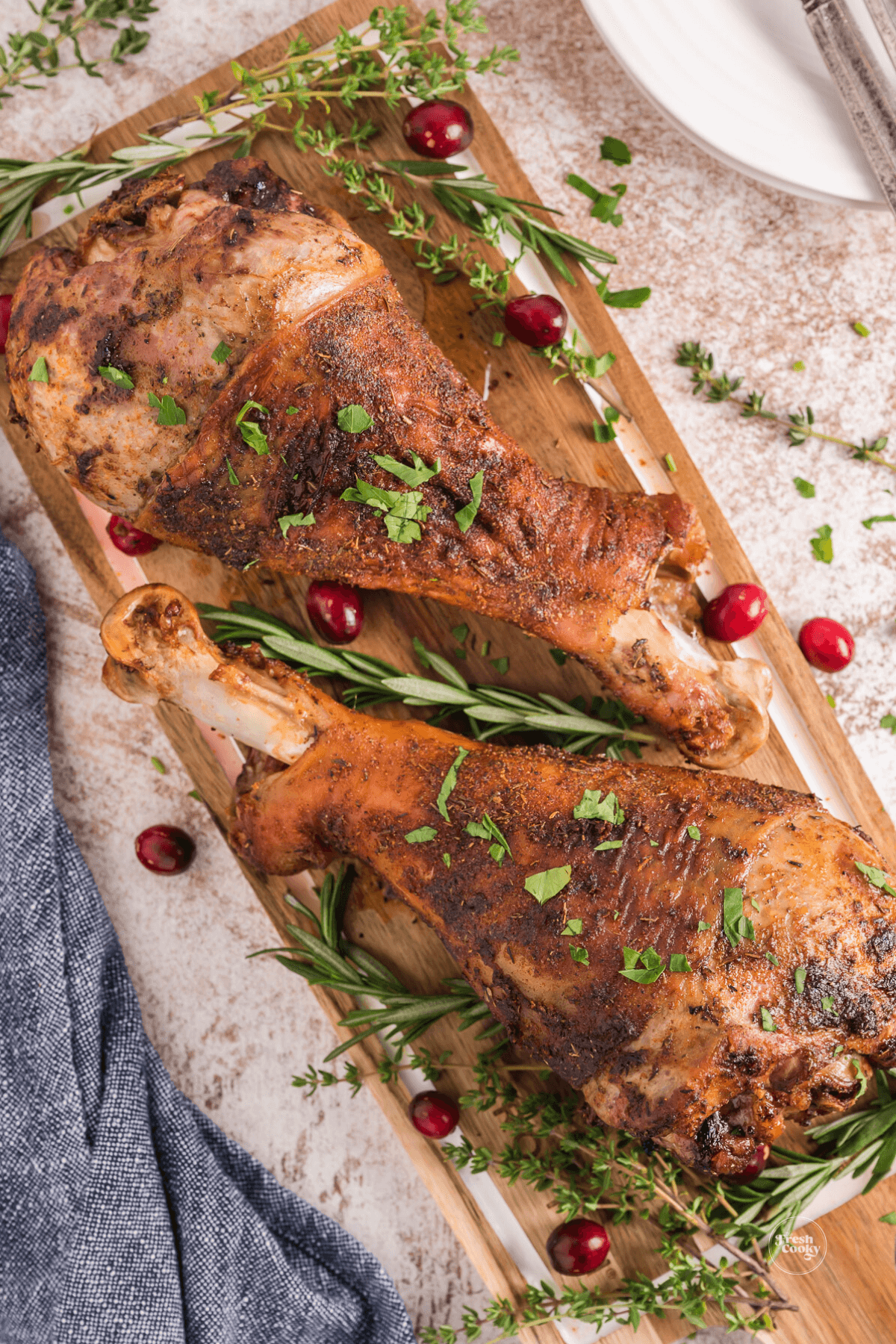 Air Fryer Turkey legs sprinkled with parsley and herbs, with cranberries.