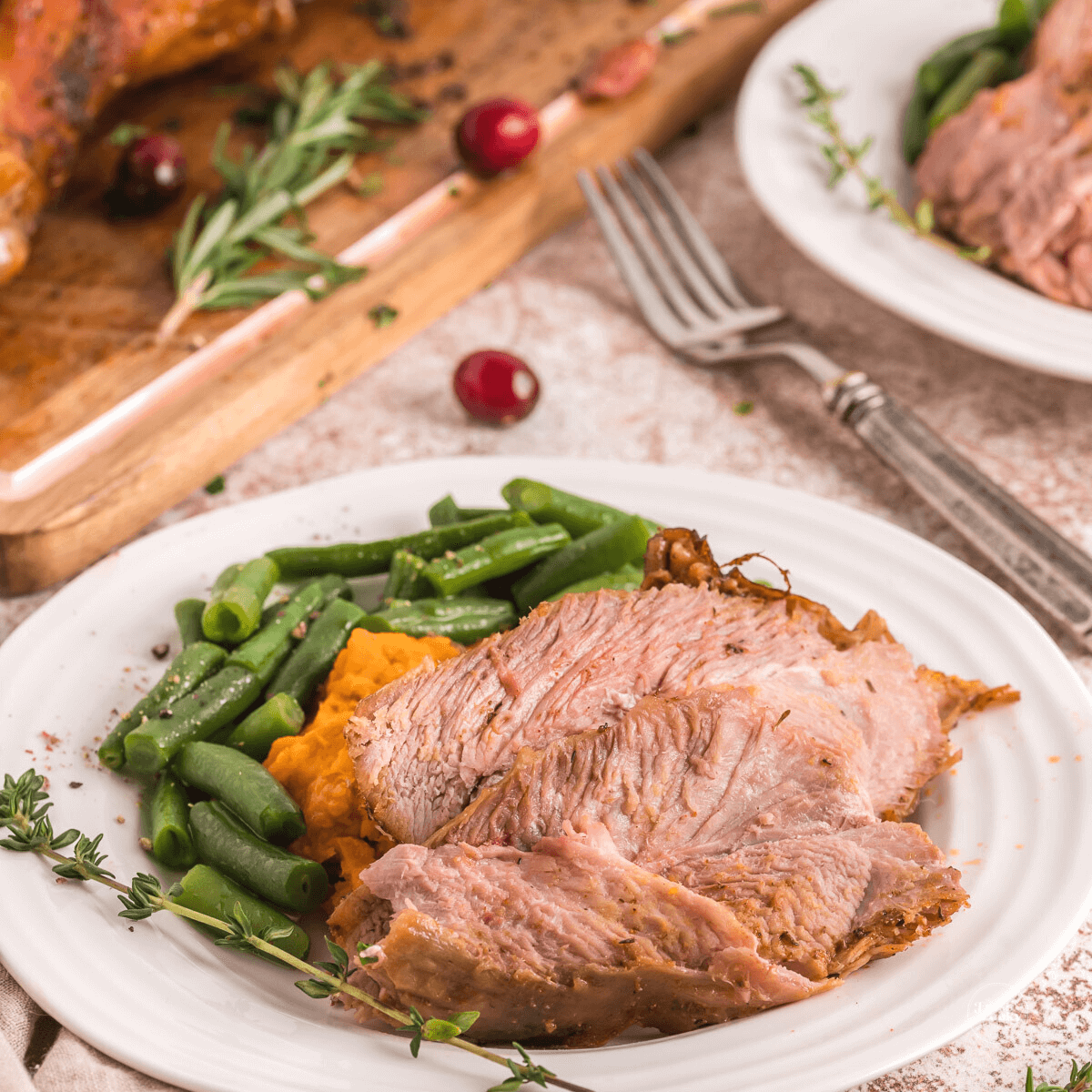 Plate filled with two juices slices of air fryer turkey leg meat, green beans and sweet potatoes.