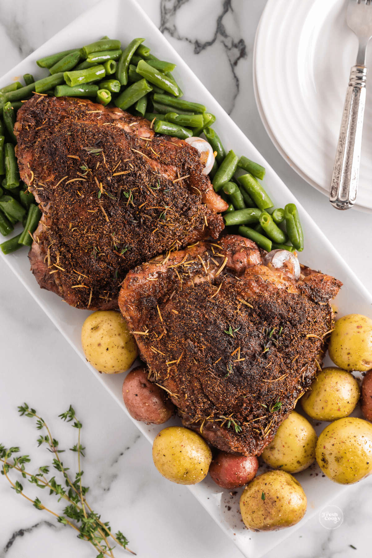 Crispy turkey thighs on platter with potatoes and green beans.