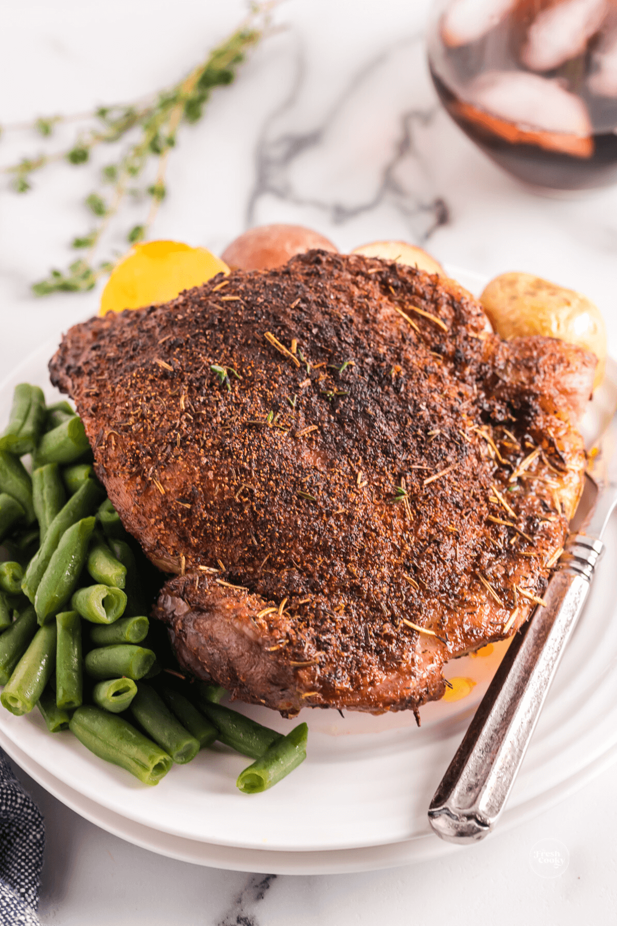 Air fryer turkey thigh on plate with green beans.