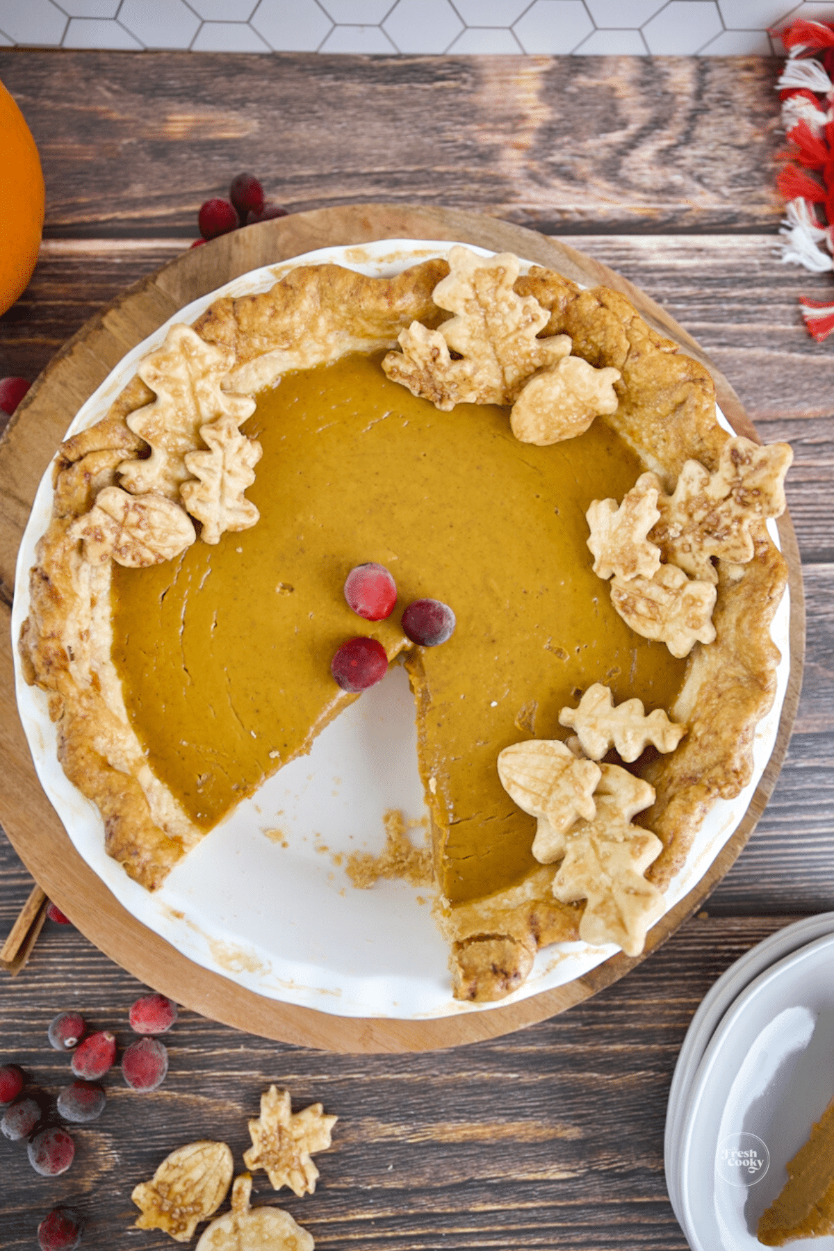 Slice removed from pumpkin pie decorated with pastry cutouts.