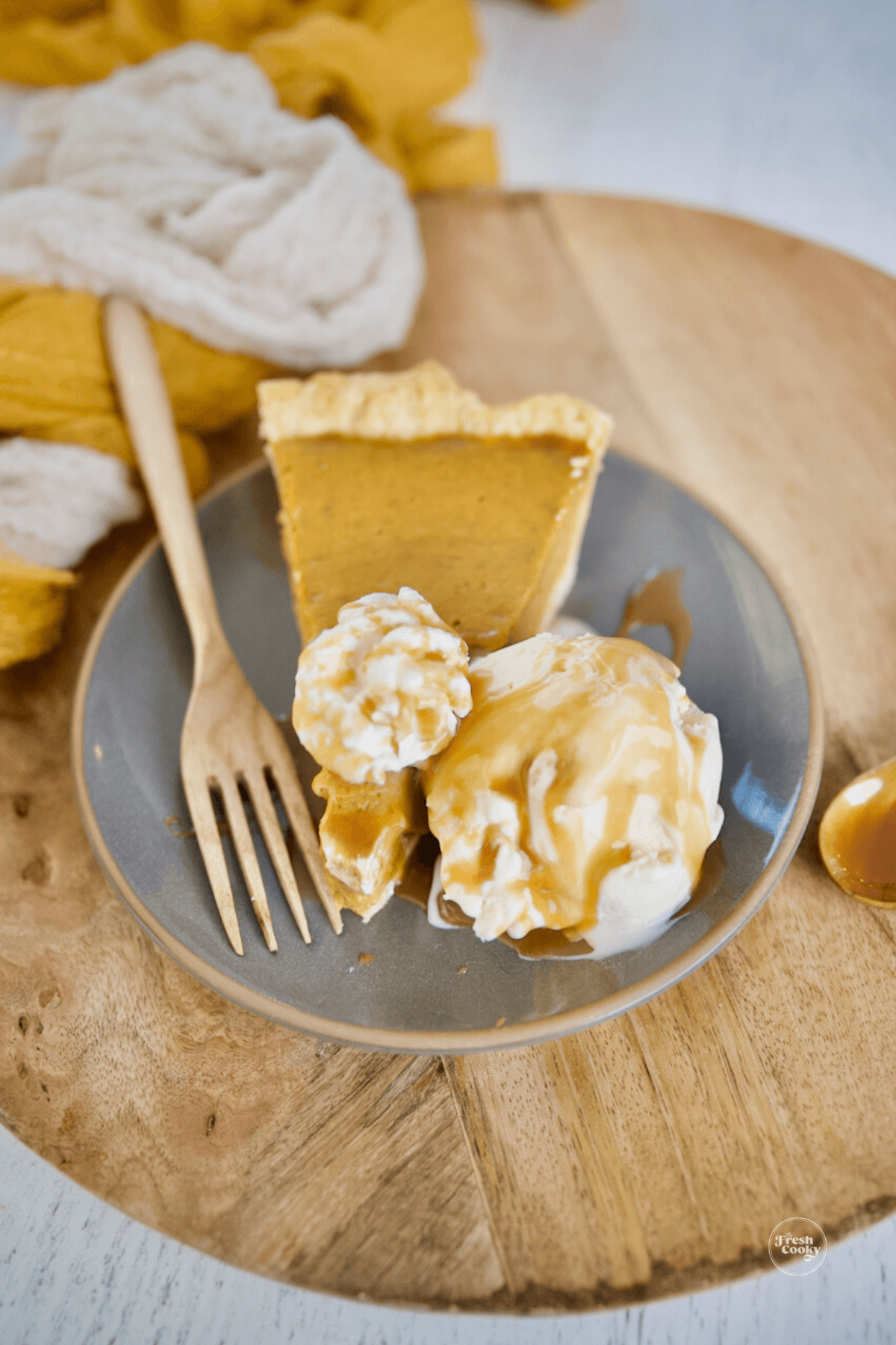 Slice of pumpkin custard pie with ice cream and a drizzle of caramel.