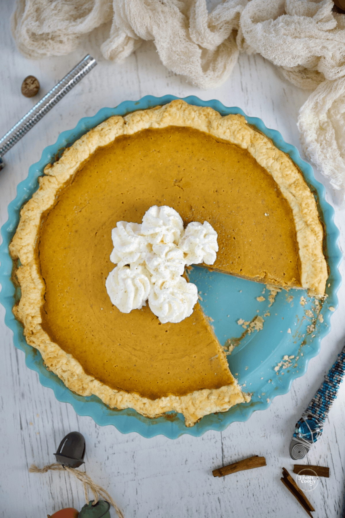 Pumpkin custard pie with slice removed and whipped cream in center.