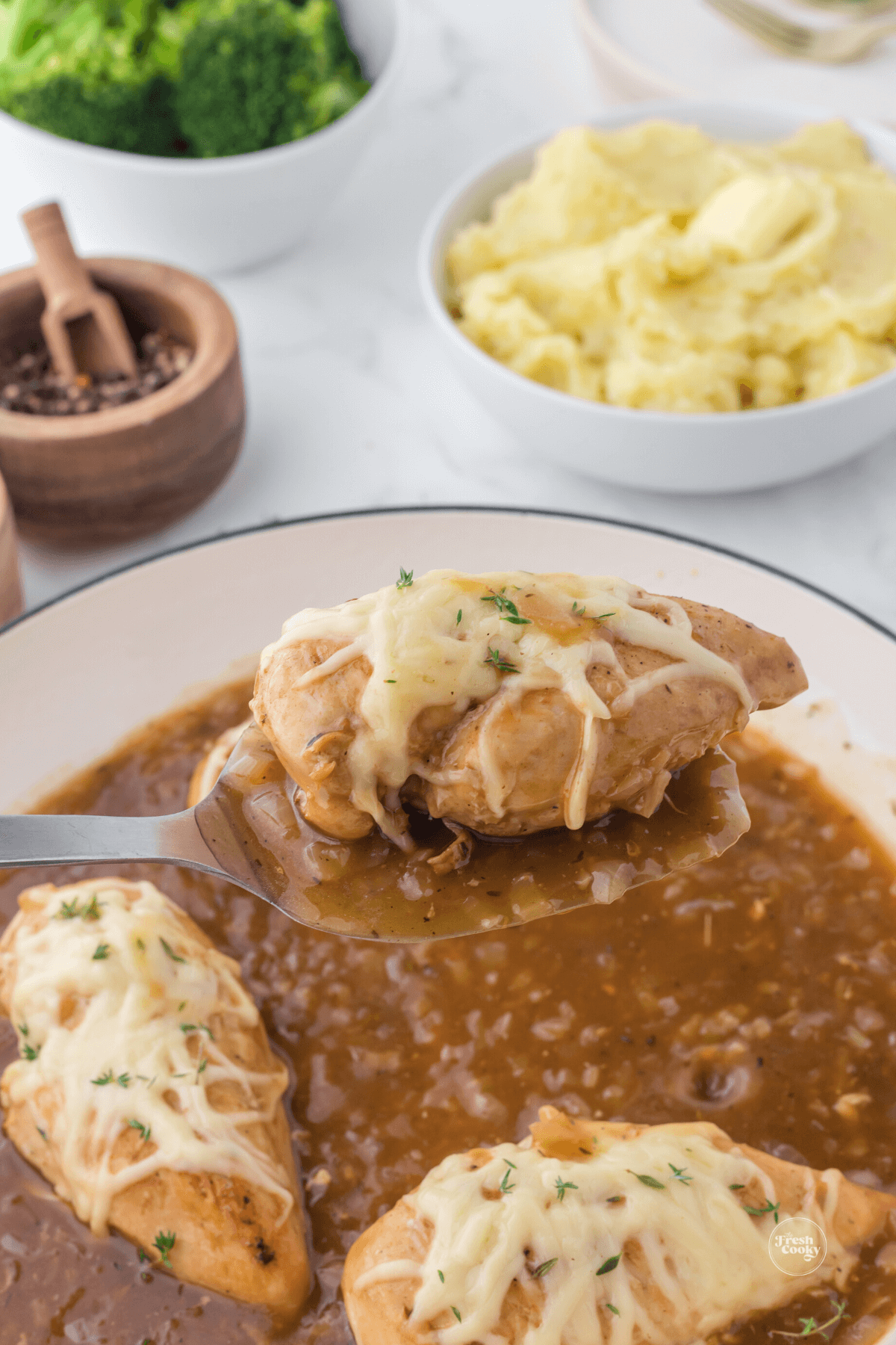 French onion chicken skillet with chicken breast on spoon.