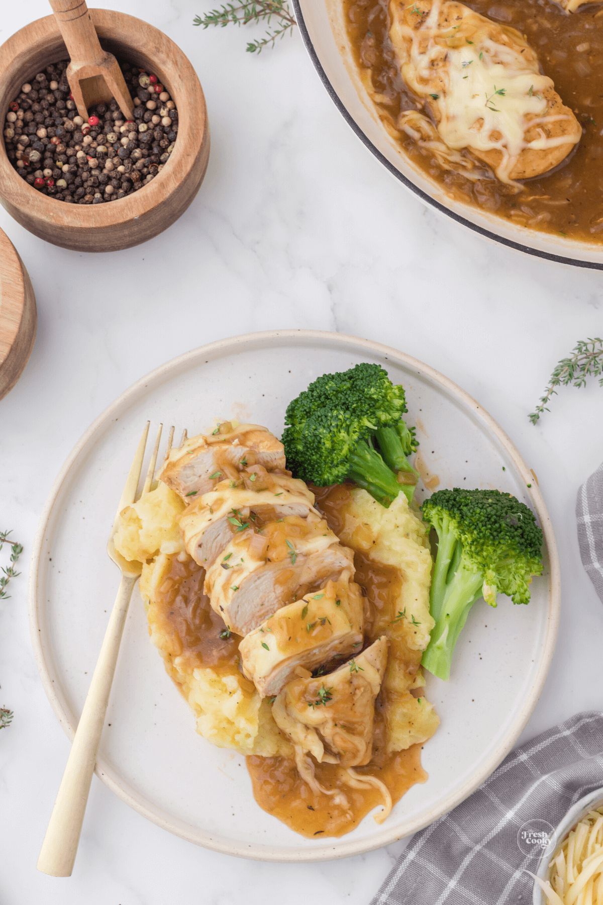 French onion chicken sliced on bed of mashed potatoes and broccoli.