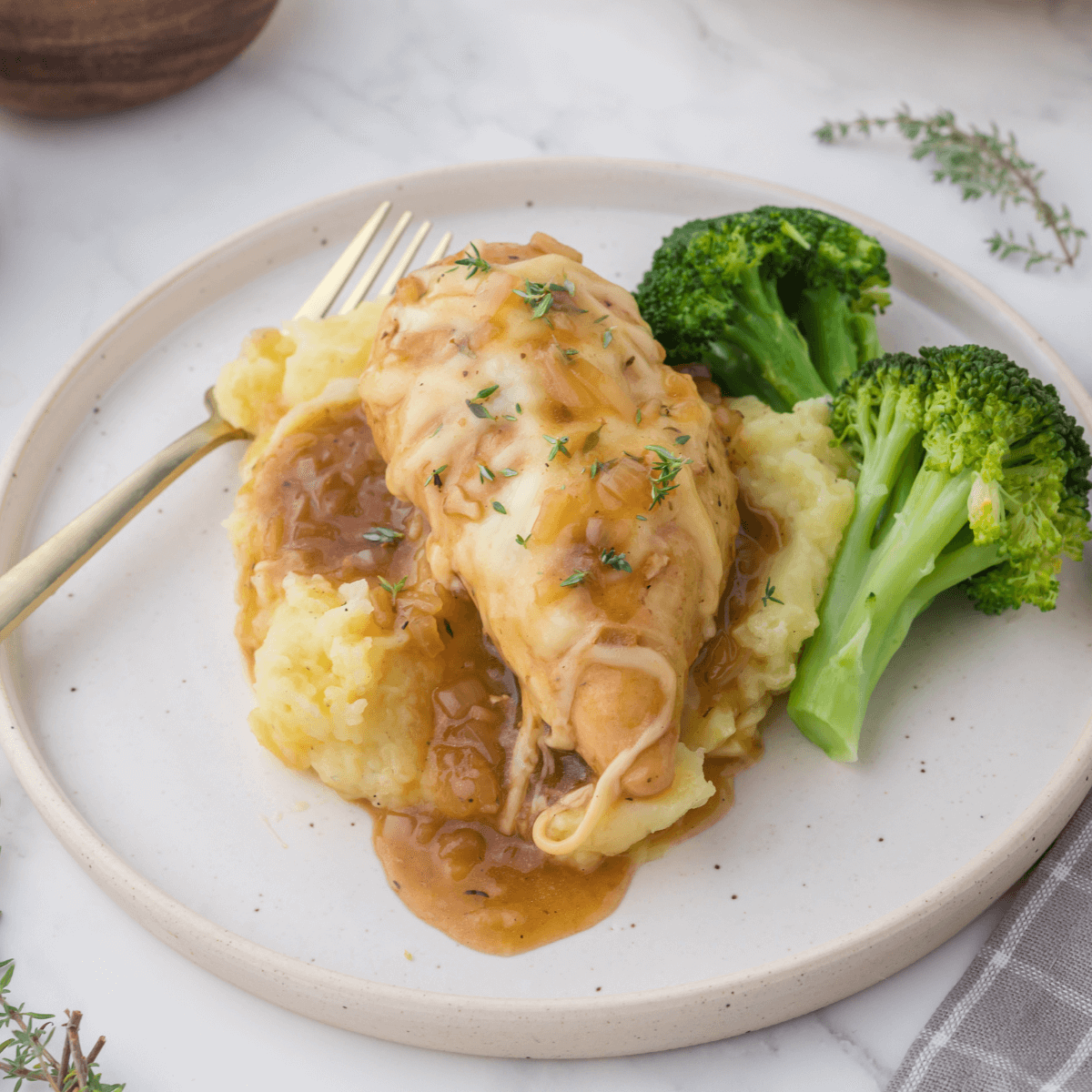 French Onion Chicken on bed of mashed potatoes with broccoli.