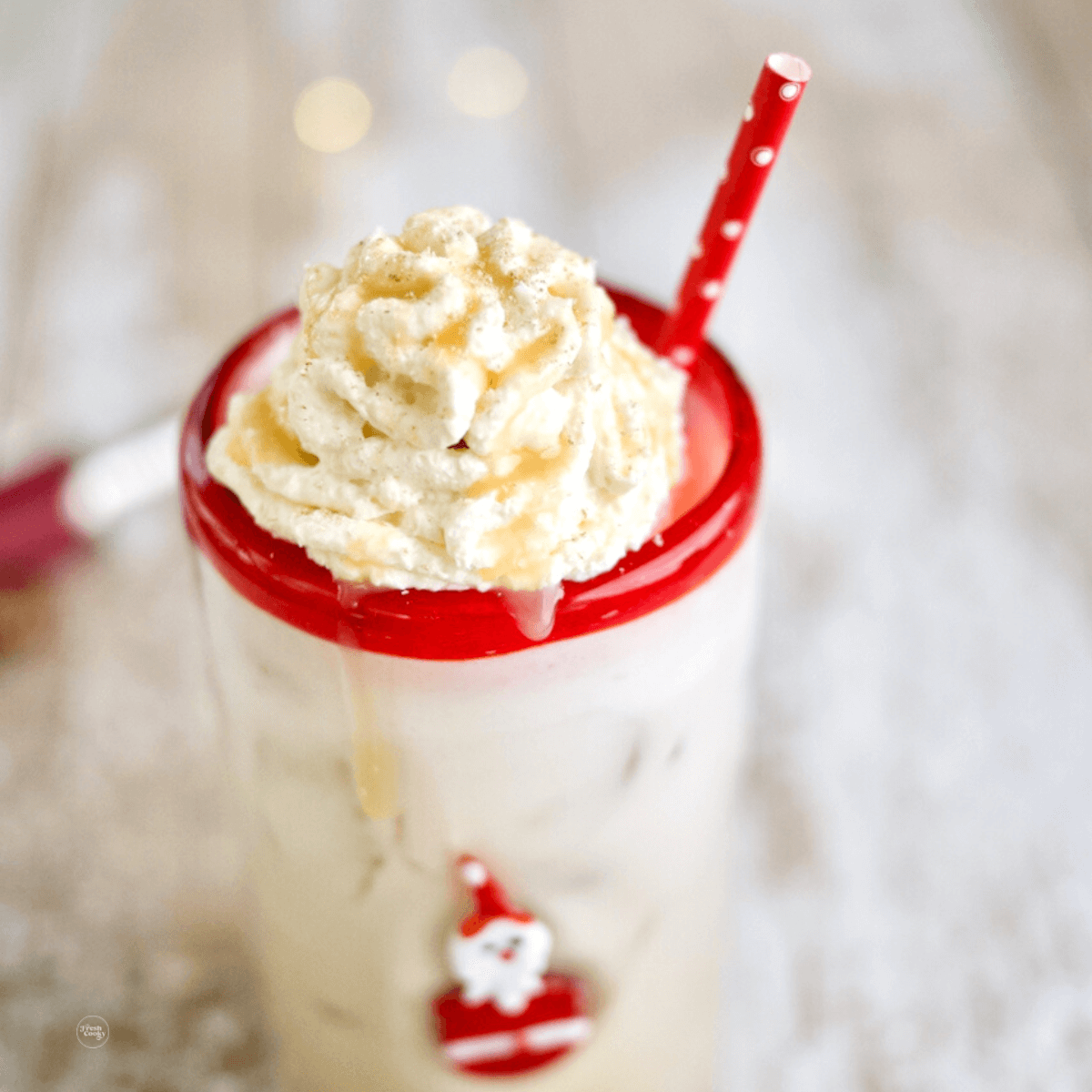 Iced Christmas Morning Chai with cute Santa glass and red and white polka dot straw.