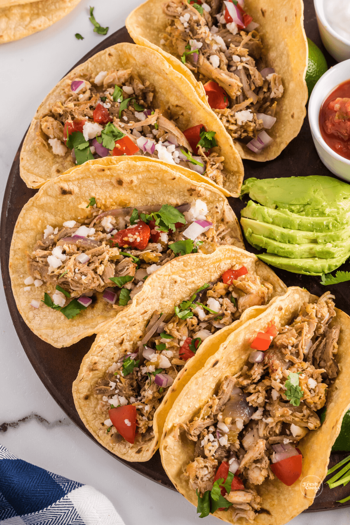 6 turkey tacos on platter with avocado and toppings.
