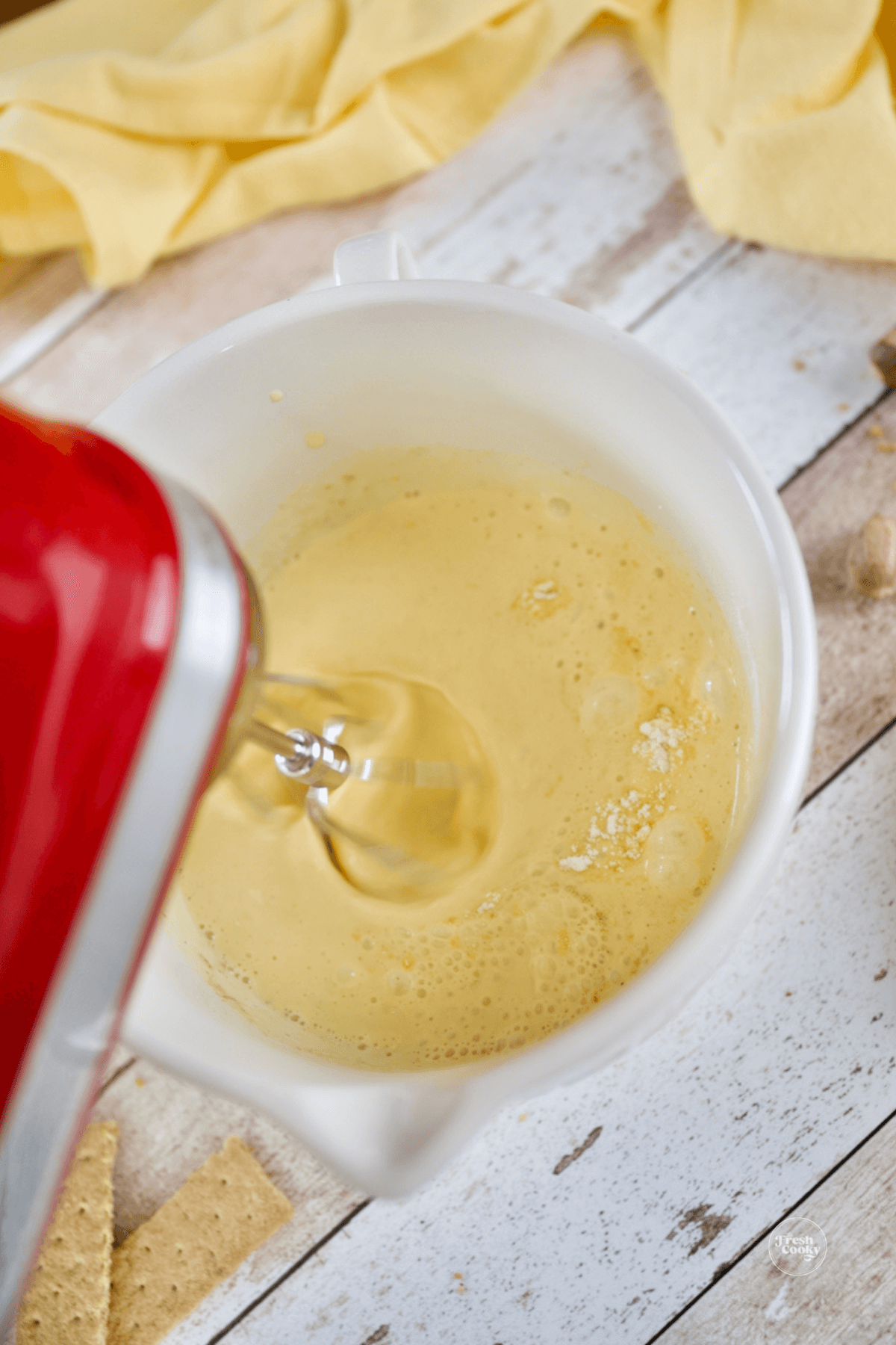 Mixing eggnog and vanilla instant pudding in bowl with hand mixer. 