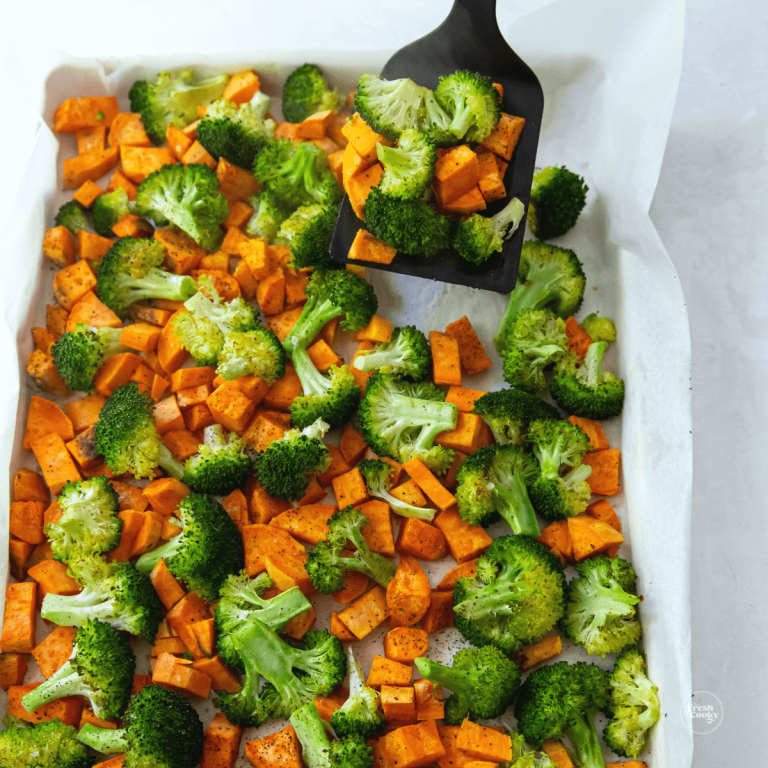 Roasted sweet potatoes and broccoli on tray with spatula.