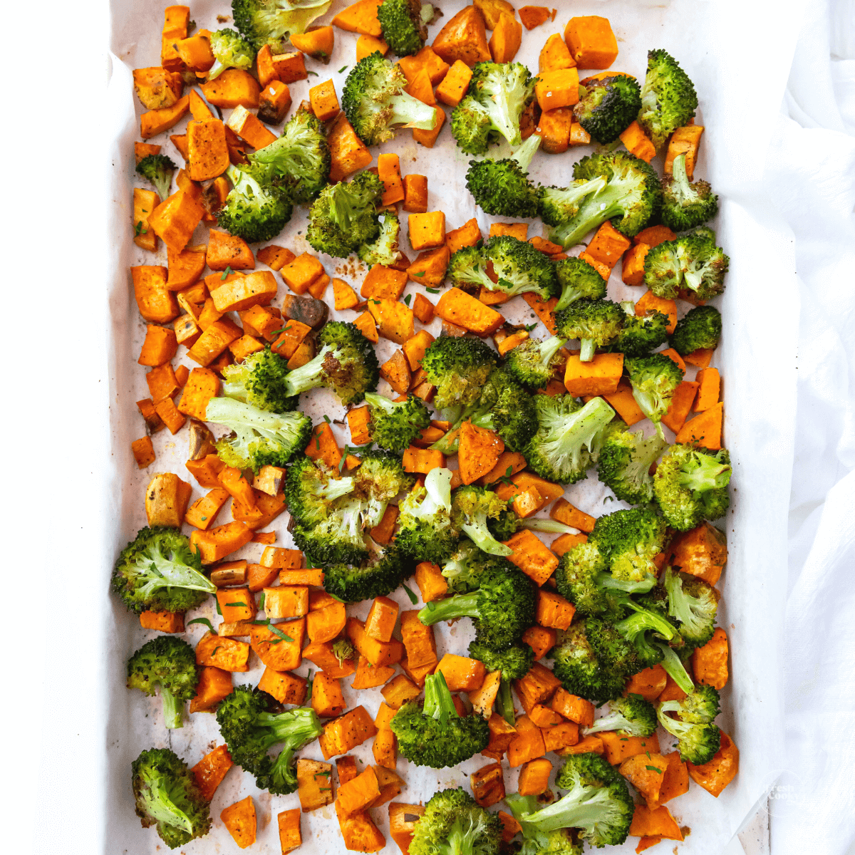 Roasted broccoli and sweet potatoes on baking sheet, roasted.