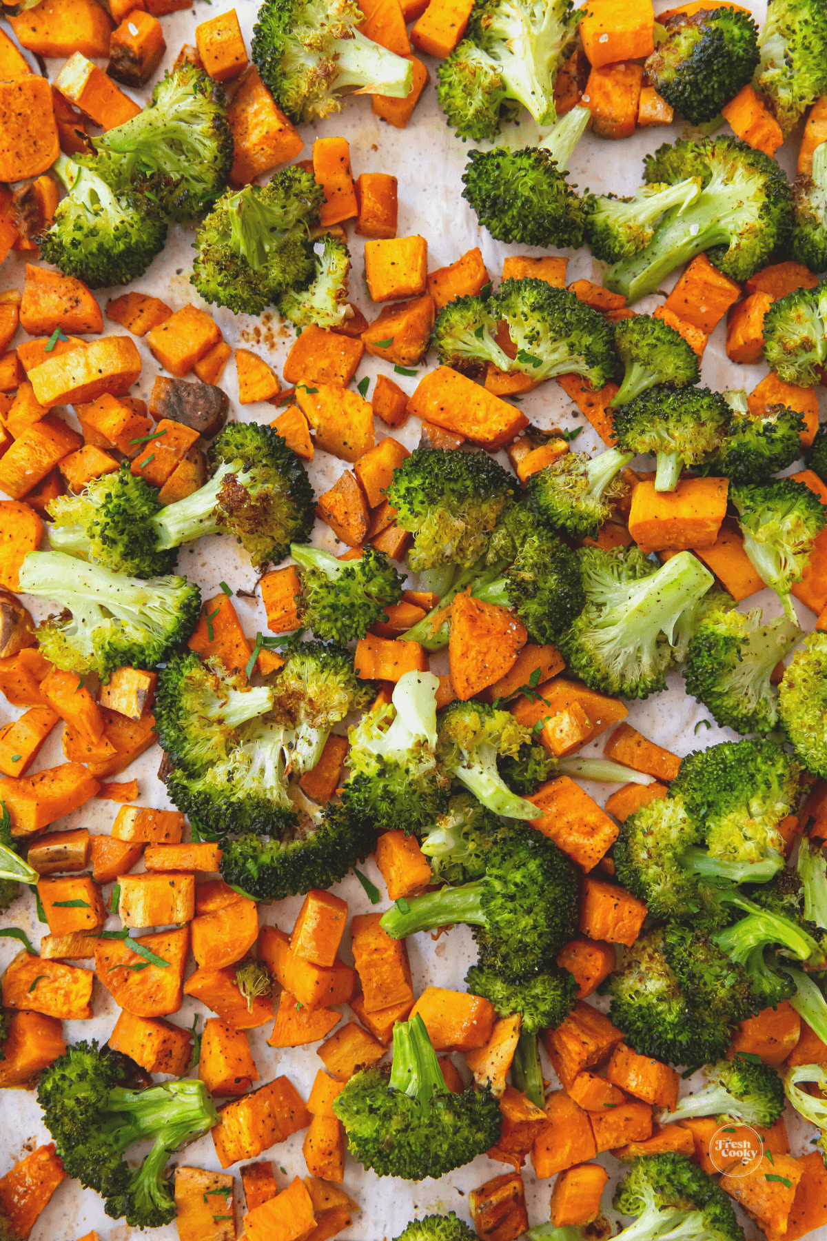 Roasted broccoli and sweet potatoes on baking sheet.