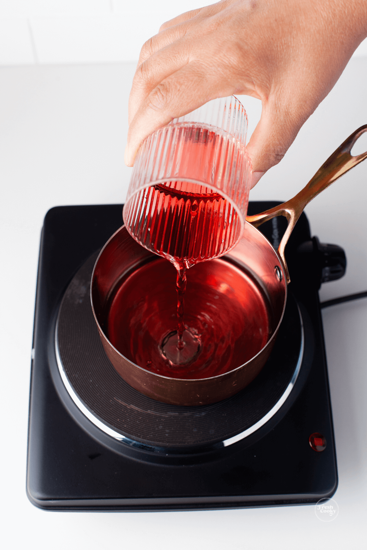 Pouring pomegranate juice into sauce pan.