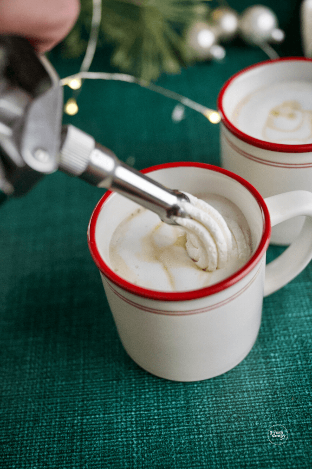 Adding whipped cream to top of Christmas morning chai.