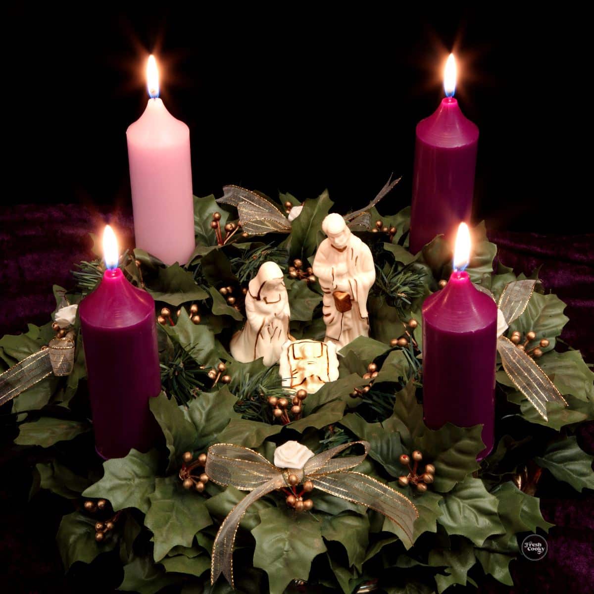 Advent wreath with lit candles and a nativity in the center.