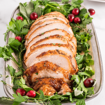 Boneless air fryer turkey breast on platter, sliced.