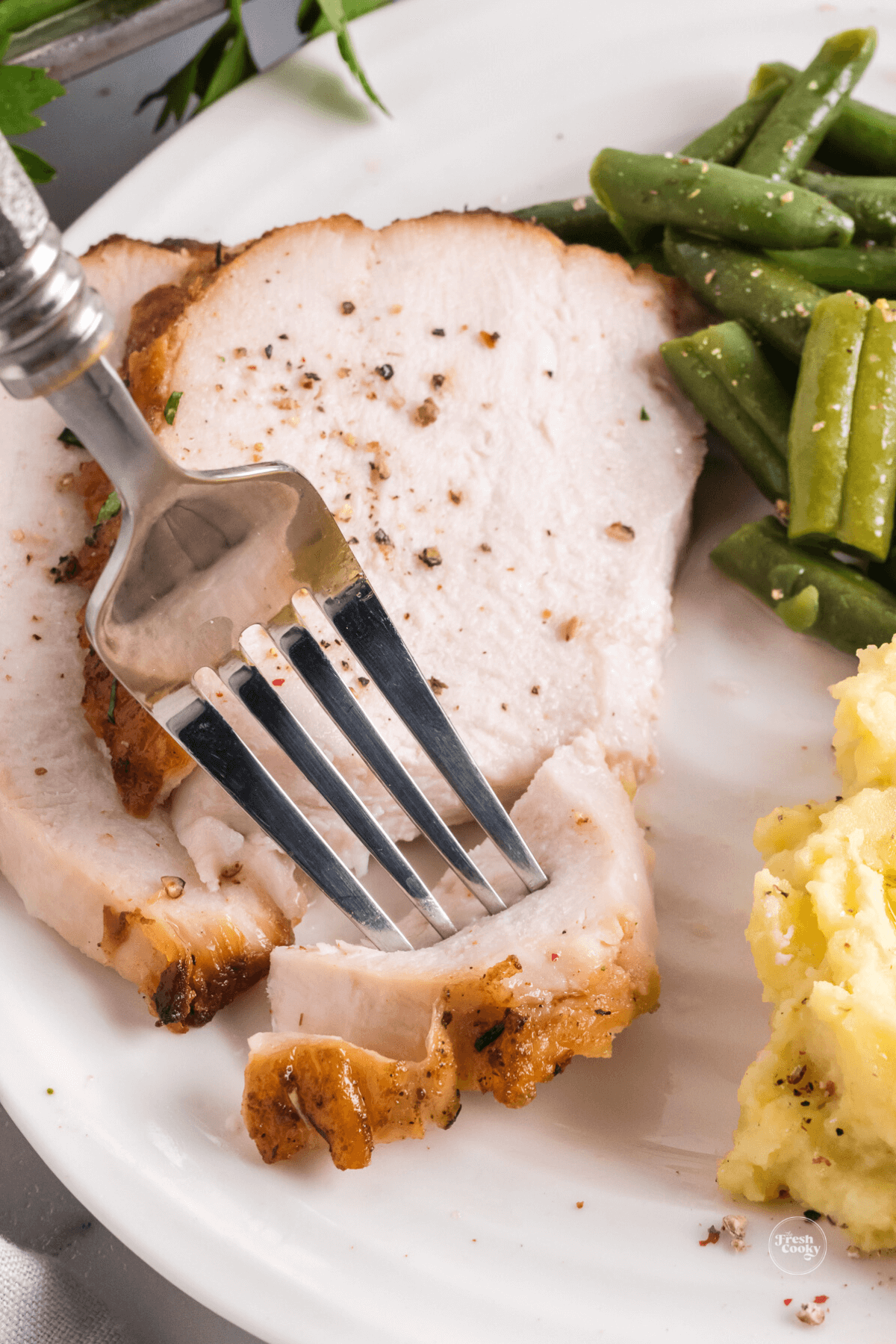 Tender turkey breast on plate with fork taking a bite.