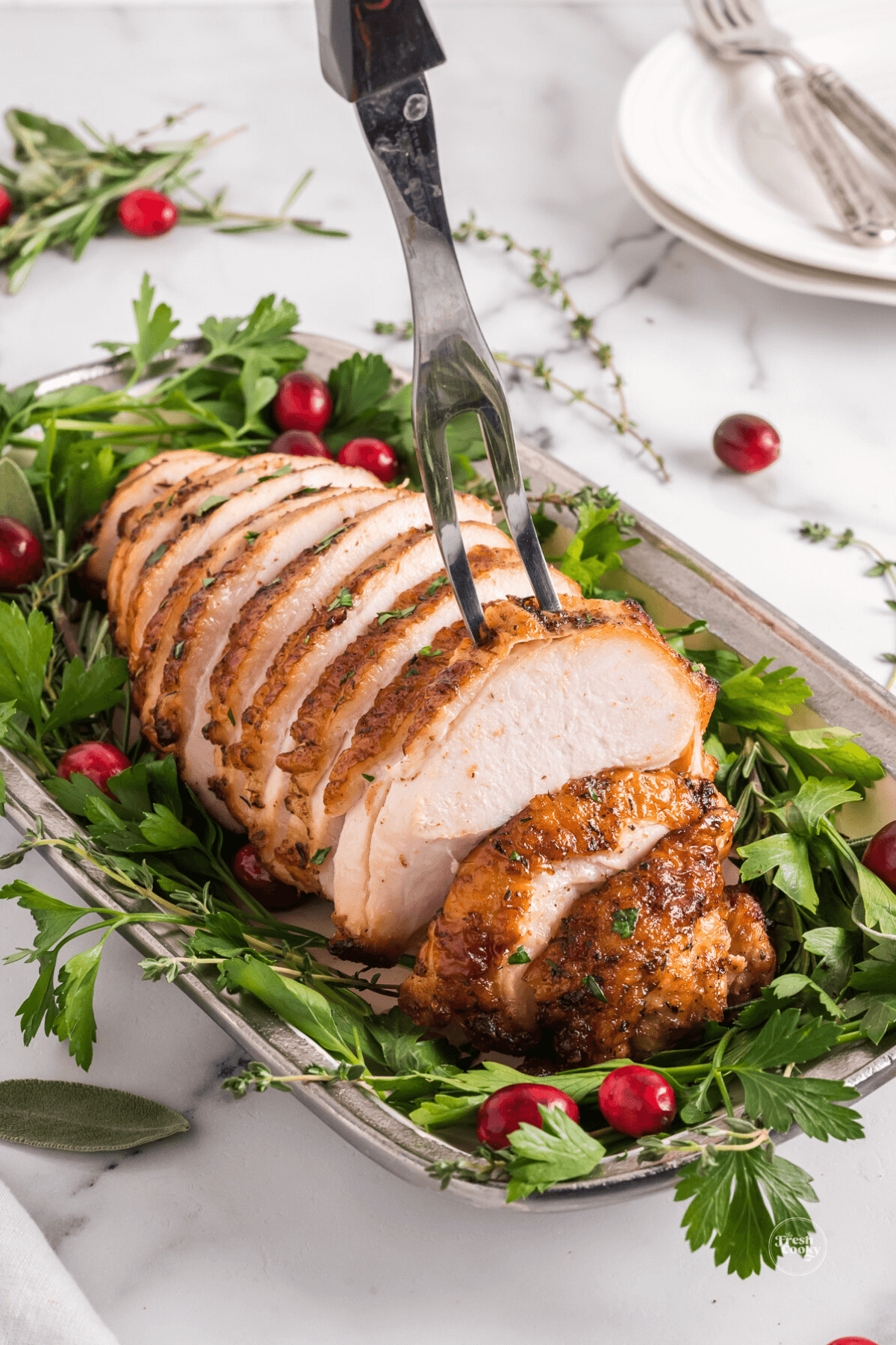 Air fryer turkey breast with carving fork grabbing a slice.