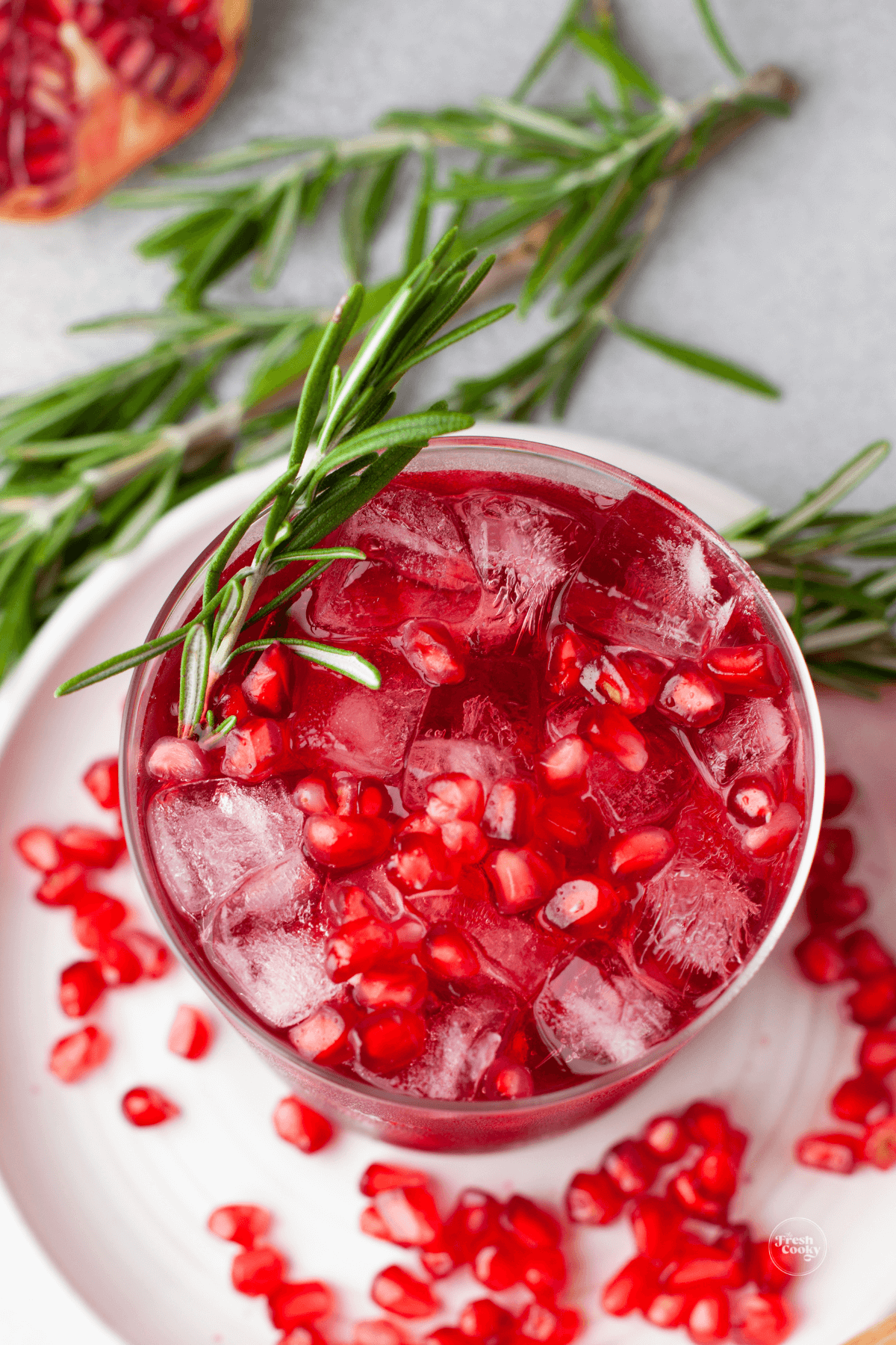 Top down view on a Christmas margarita topped with pomegranate arils and a sprig of rosemary.