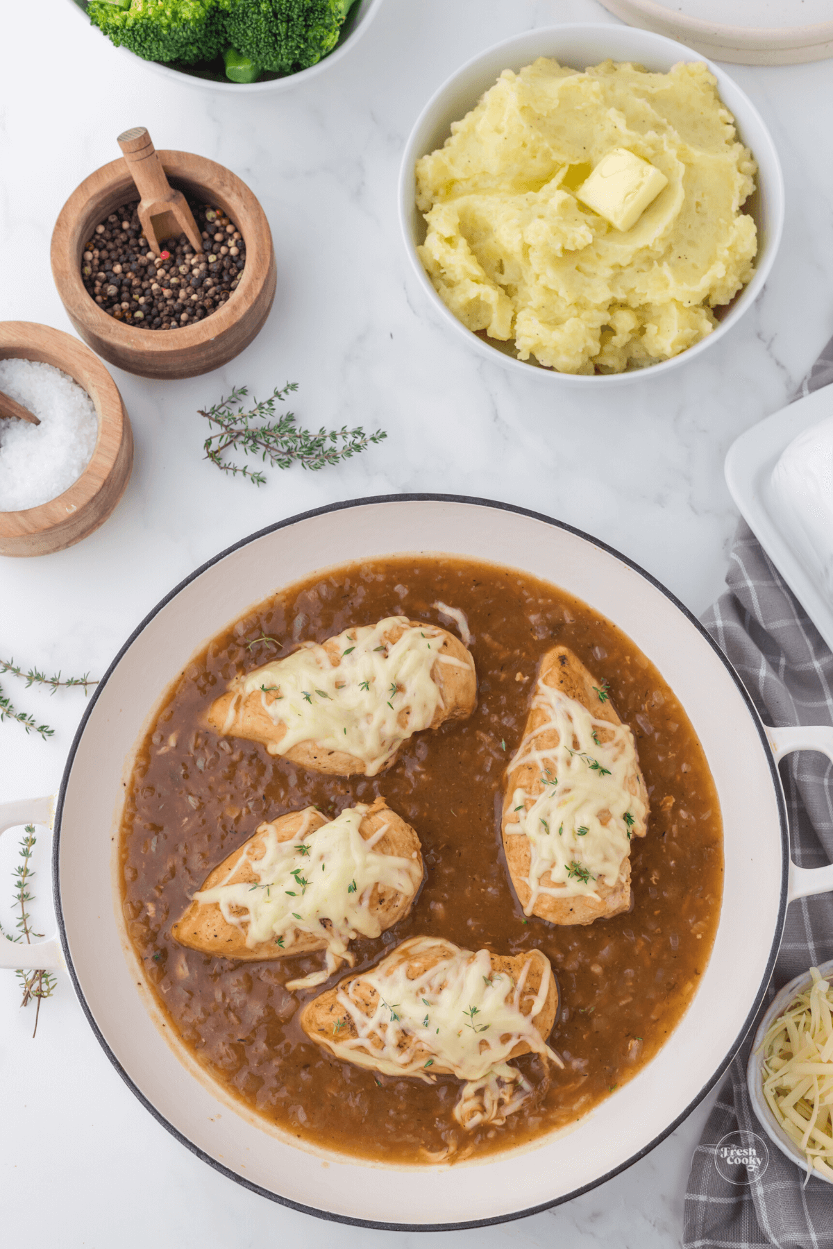 French Onion Chicken in skillet with seasonings and mashed potatoes.