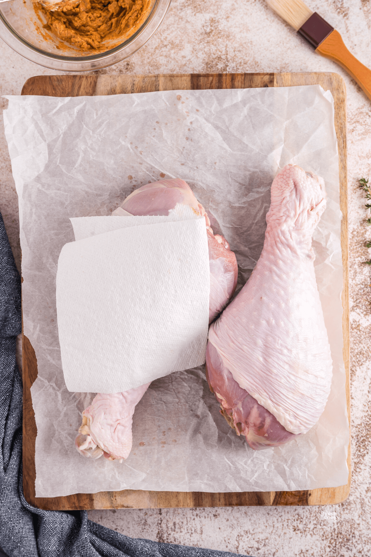 Patting turkey legs dry with paper towels. 