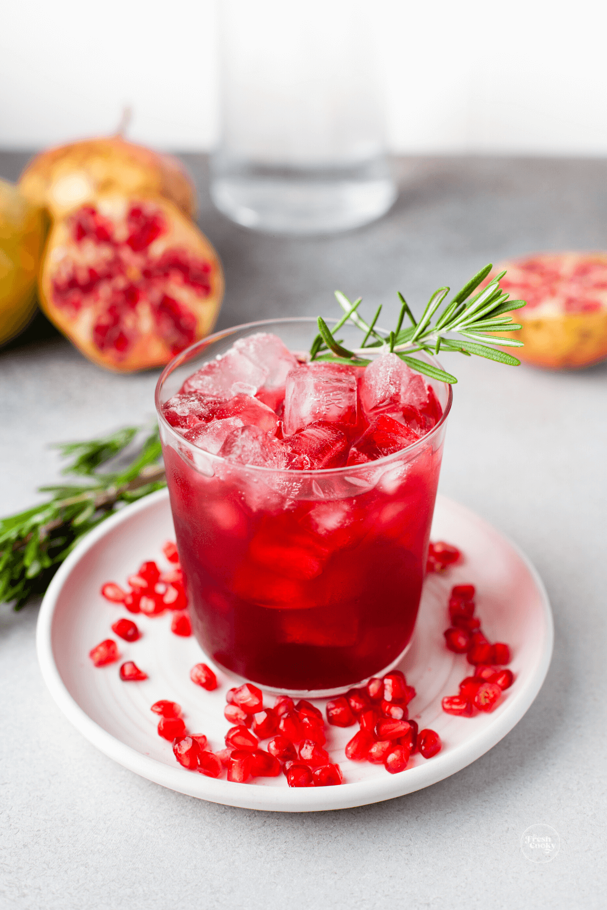 Festive Pomegranate Hibiscus Margarita with fresh pomegranate in background and arils on a plate.