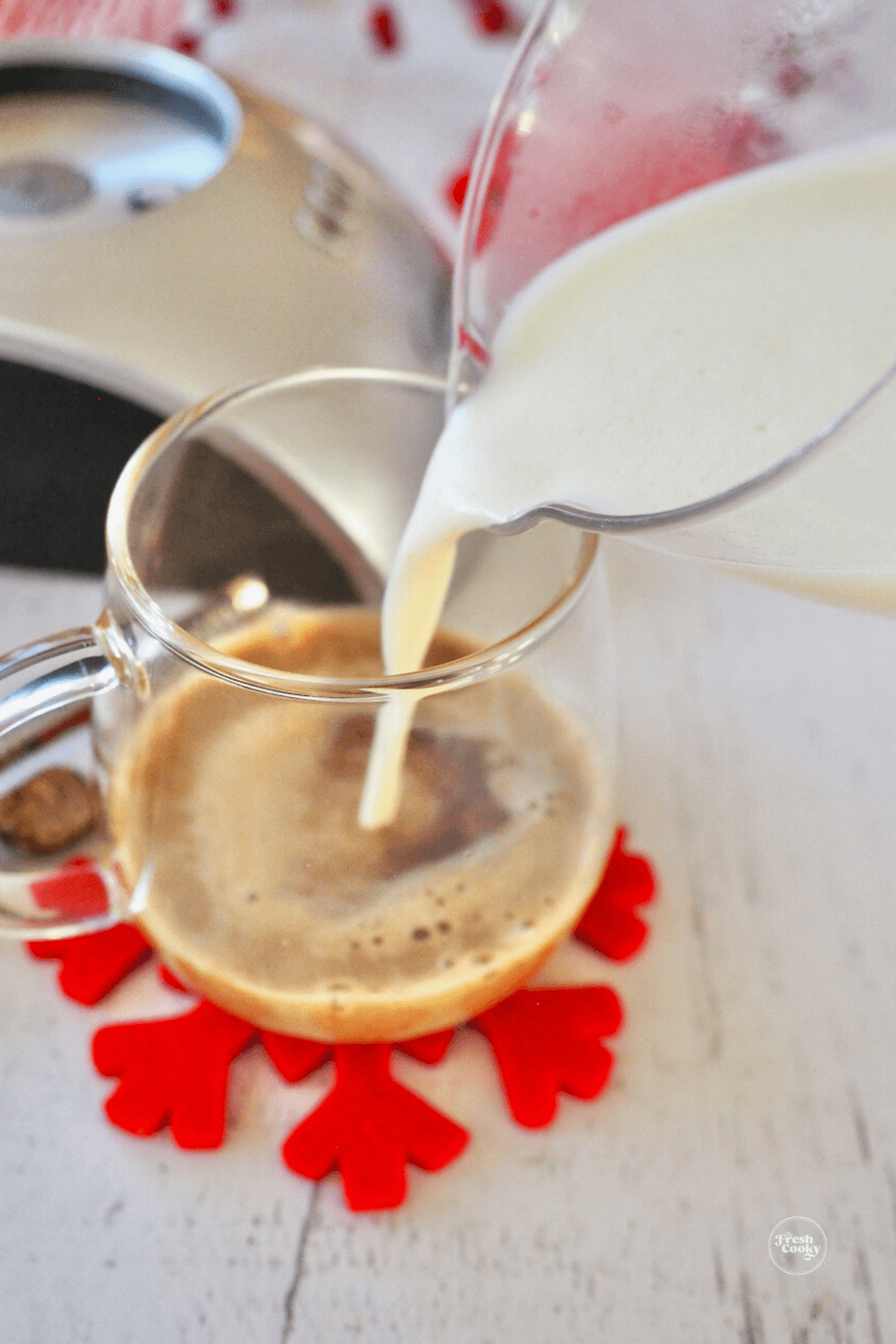 Pouring frothed eggnog and milk mixture into espresso.