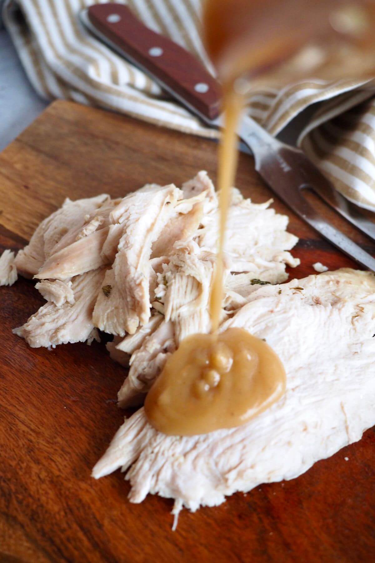 Pouring gravy onto juicy, sliced turkey breast.