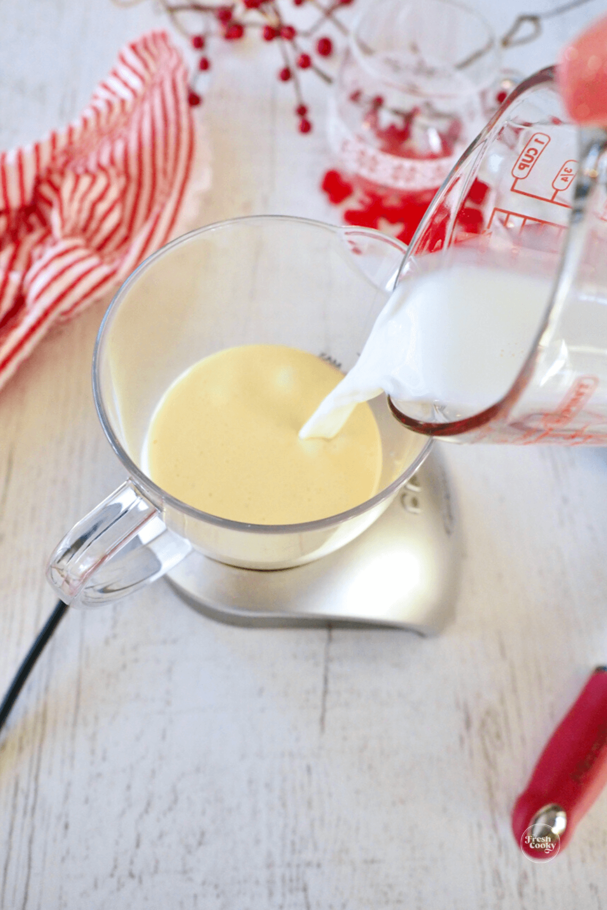 Pouring milk into eggnog in frother. 