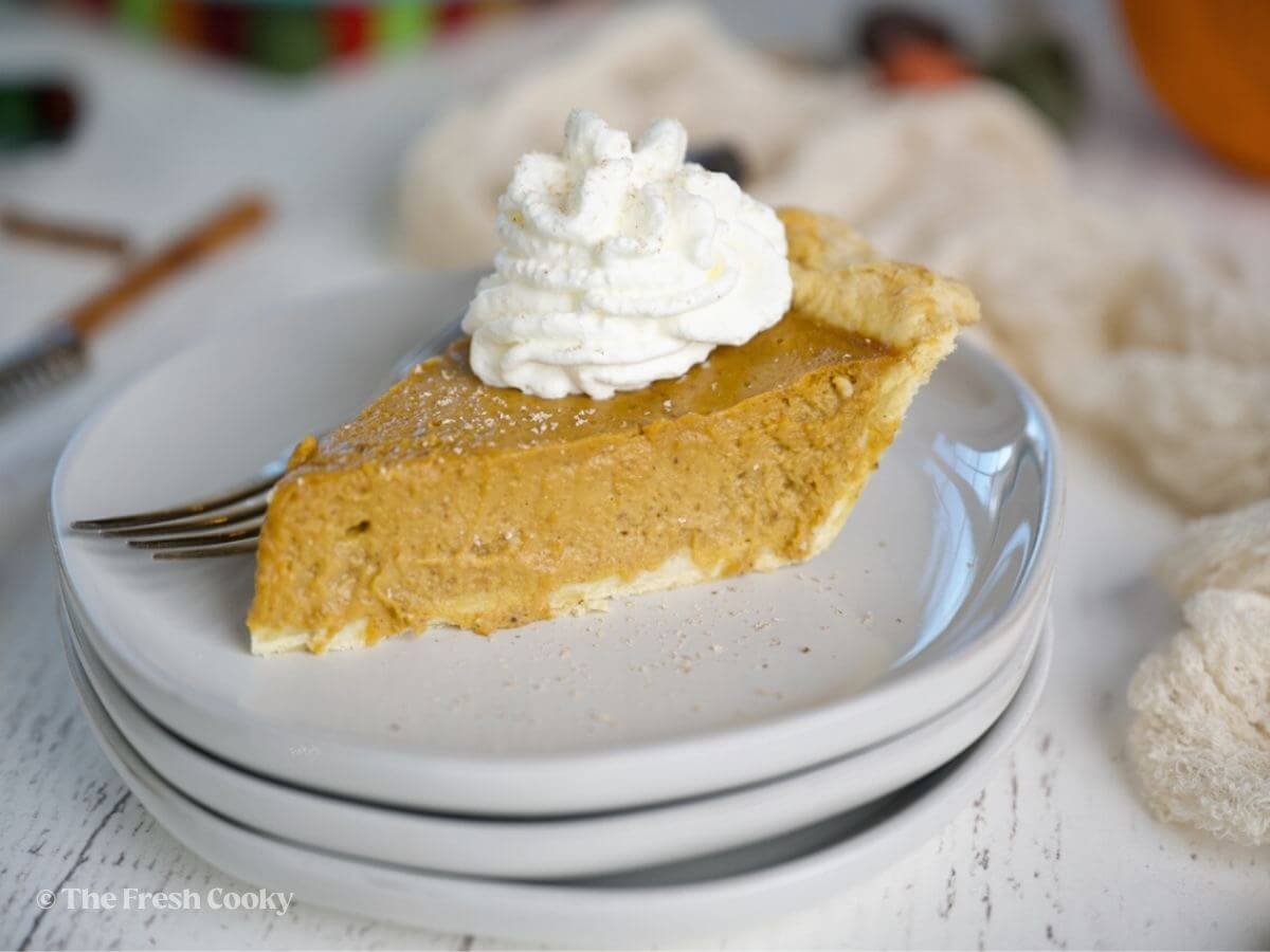 Slice of creamy, Costco custard pumpkin pie with whipped cream.