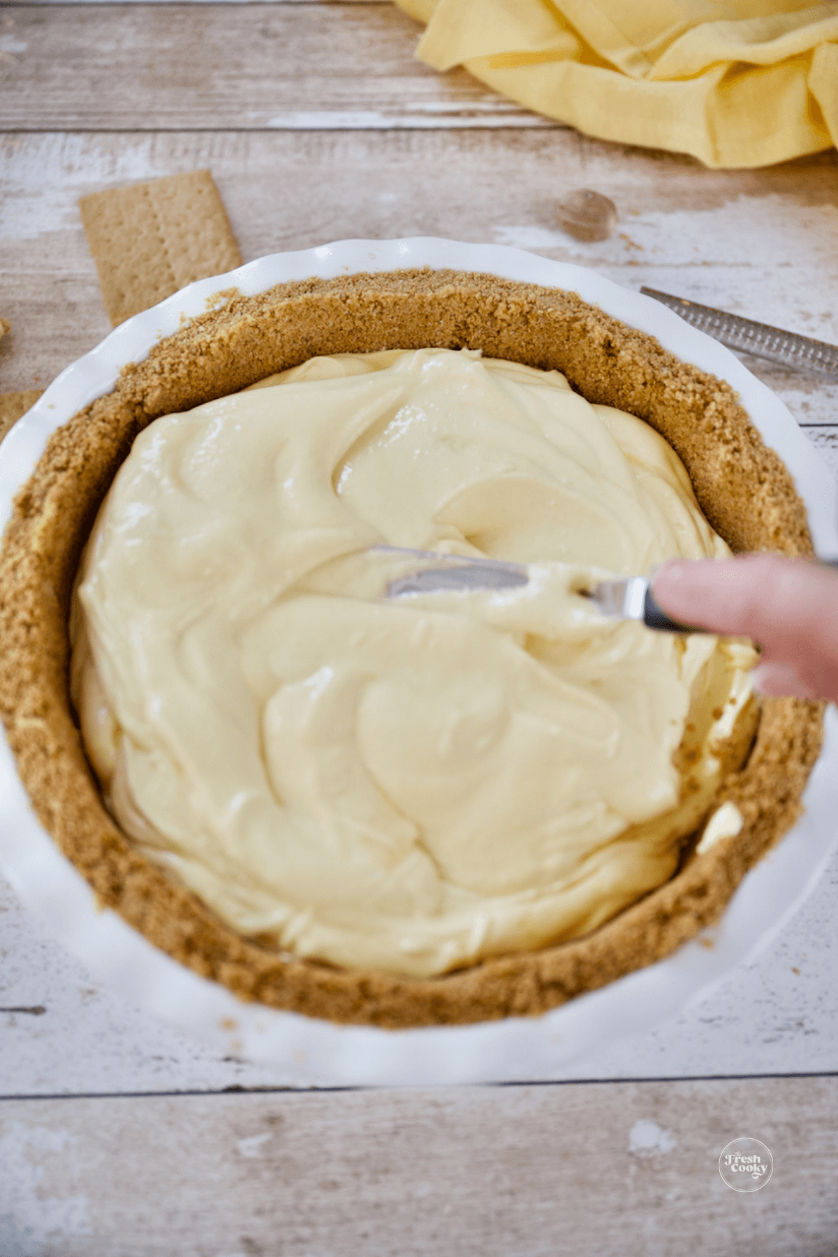 Smoothing the eggnog mixture into graham cracker crust.