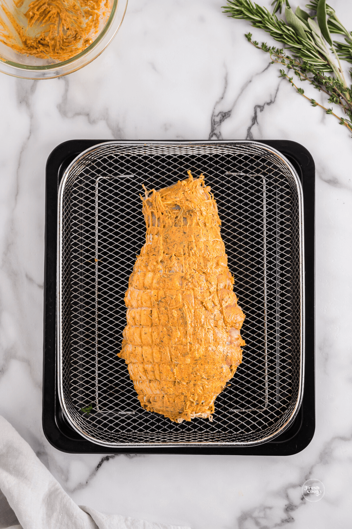 Turkey breast going into air fryer basket.