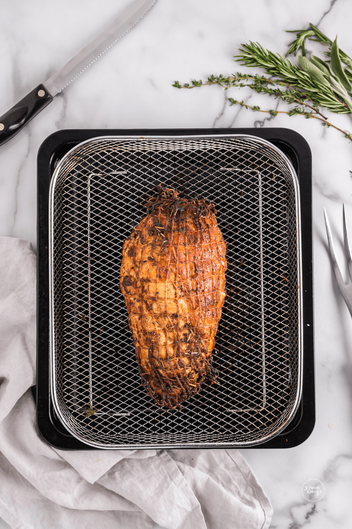 Finished air fryer roasted turkey breast on air fryer basket.
