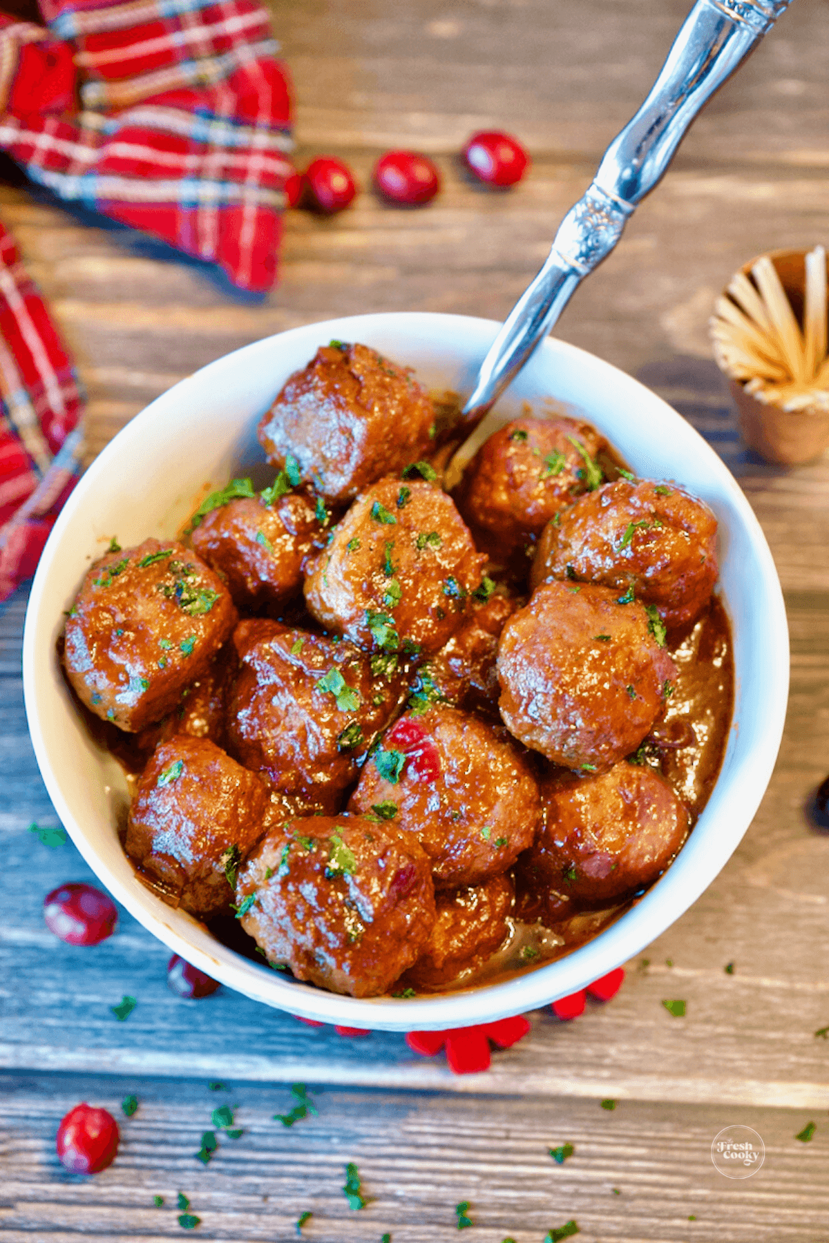 3 ingredient cranberry meatballs in bowl with serving spoon and toothpicks for cocktail appetizer.
