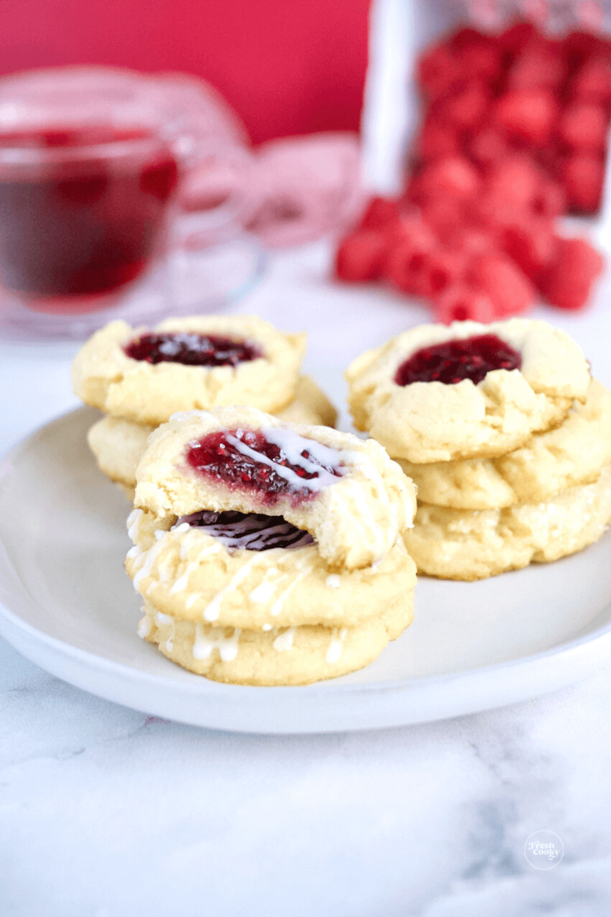 5-ingredient Raspberry Cheesecake Thumbprint Cookies on plate with bite taken out of one.