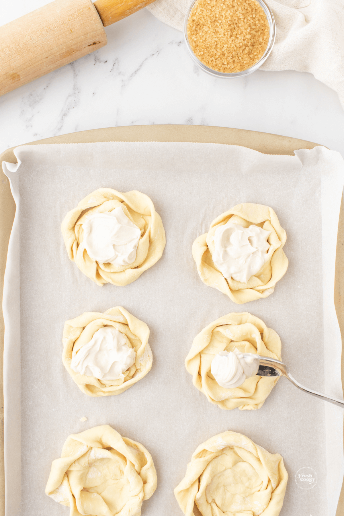 Adding dollop of cream cheese mixture to middle of pastry rounds.