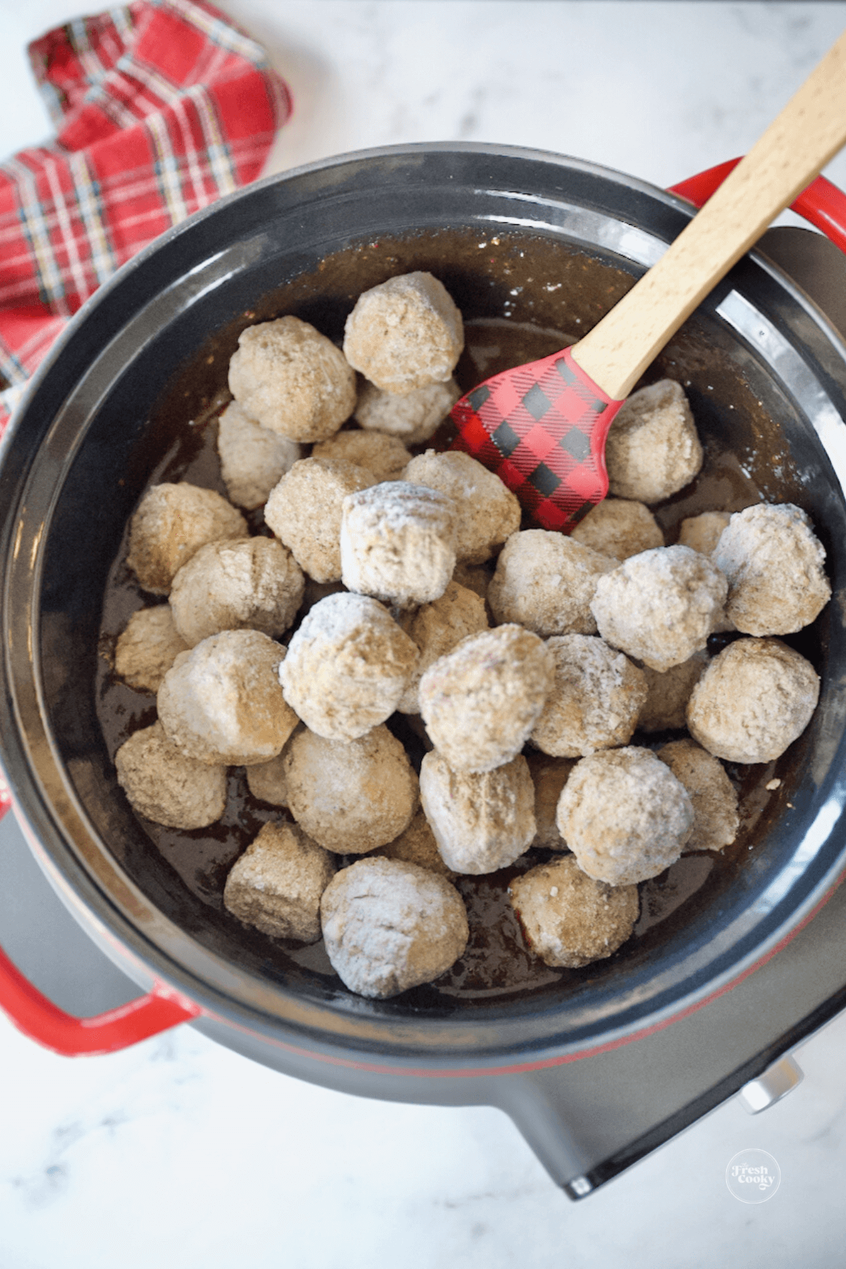 Adding frozen meatballs to crockpot.