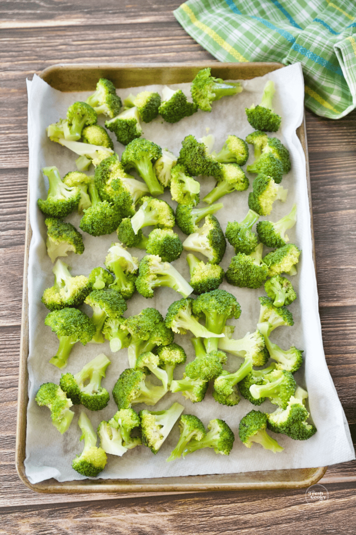 Blanched broccoli in tray with paper towels to absorb water. 