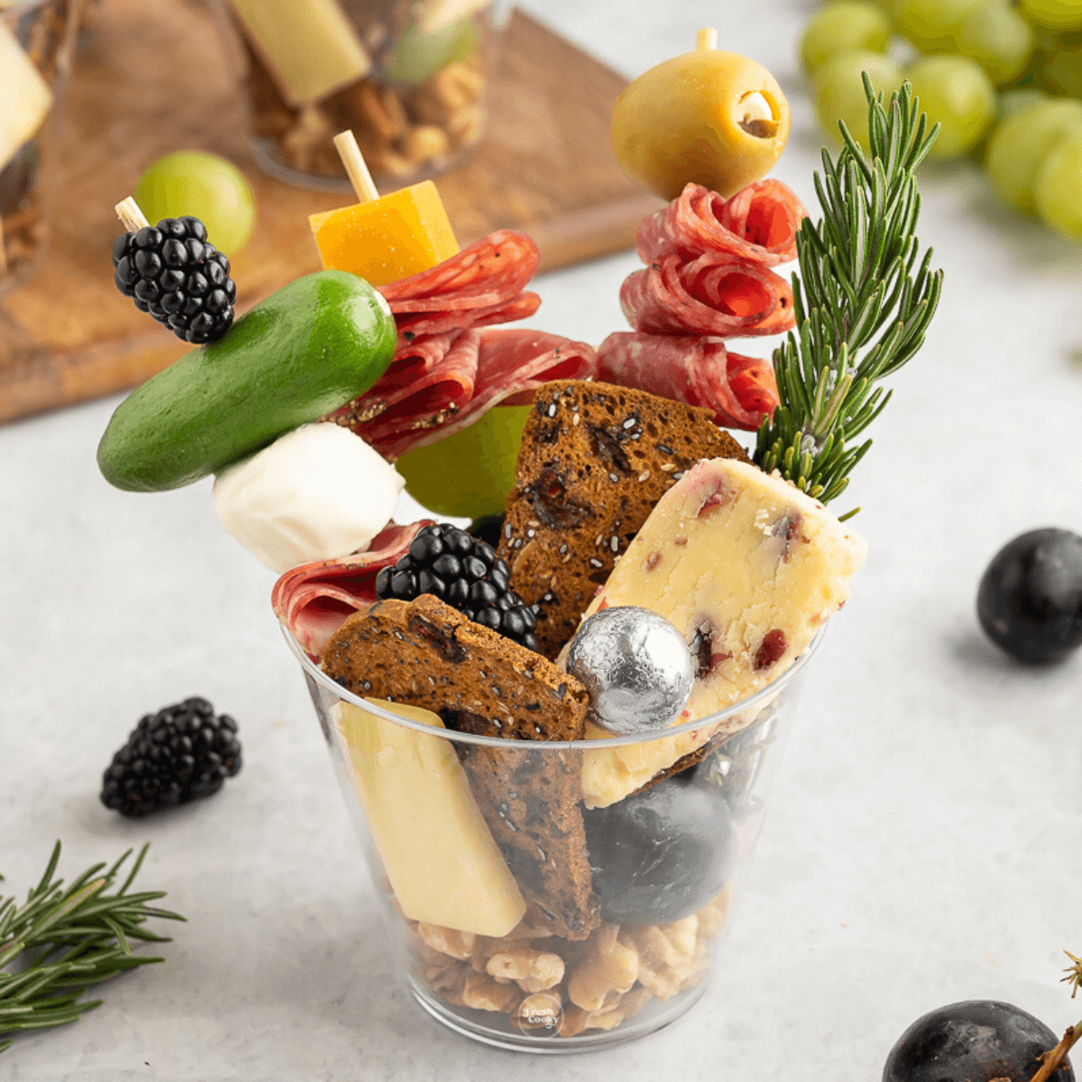 Charcuterie cup filled with cured meats, cheese, veggies on skewersand nuts and crackers. 