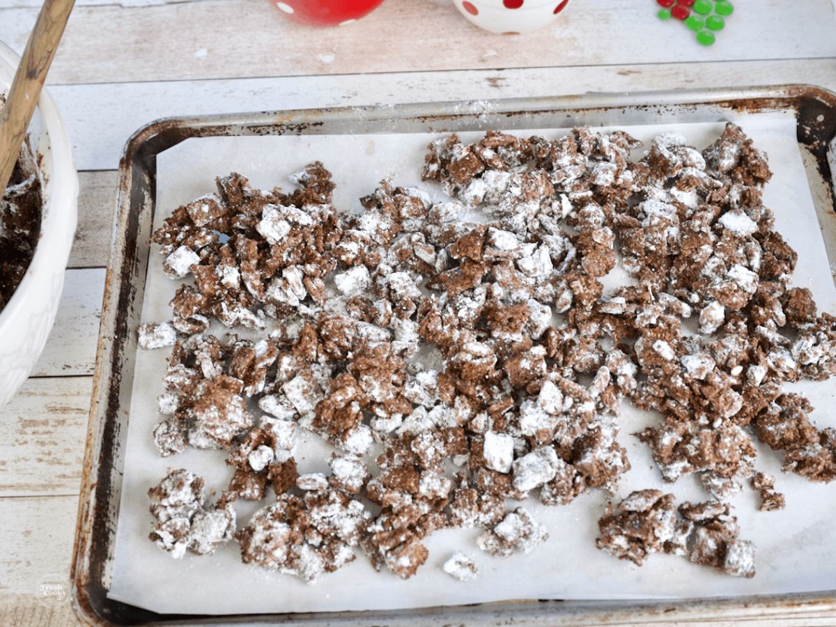 Clumpy Christmas Puppy Chow mixture on baking sheet.