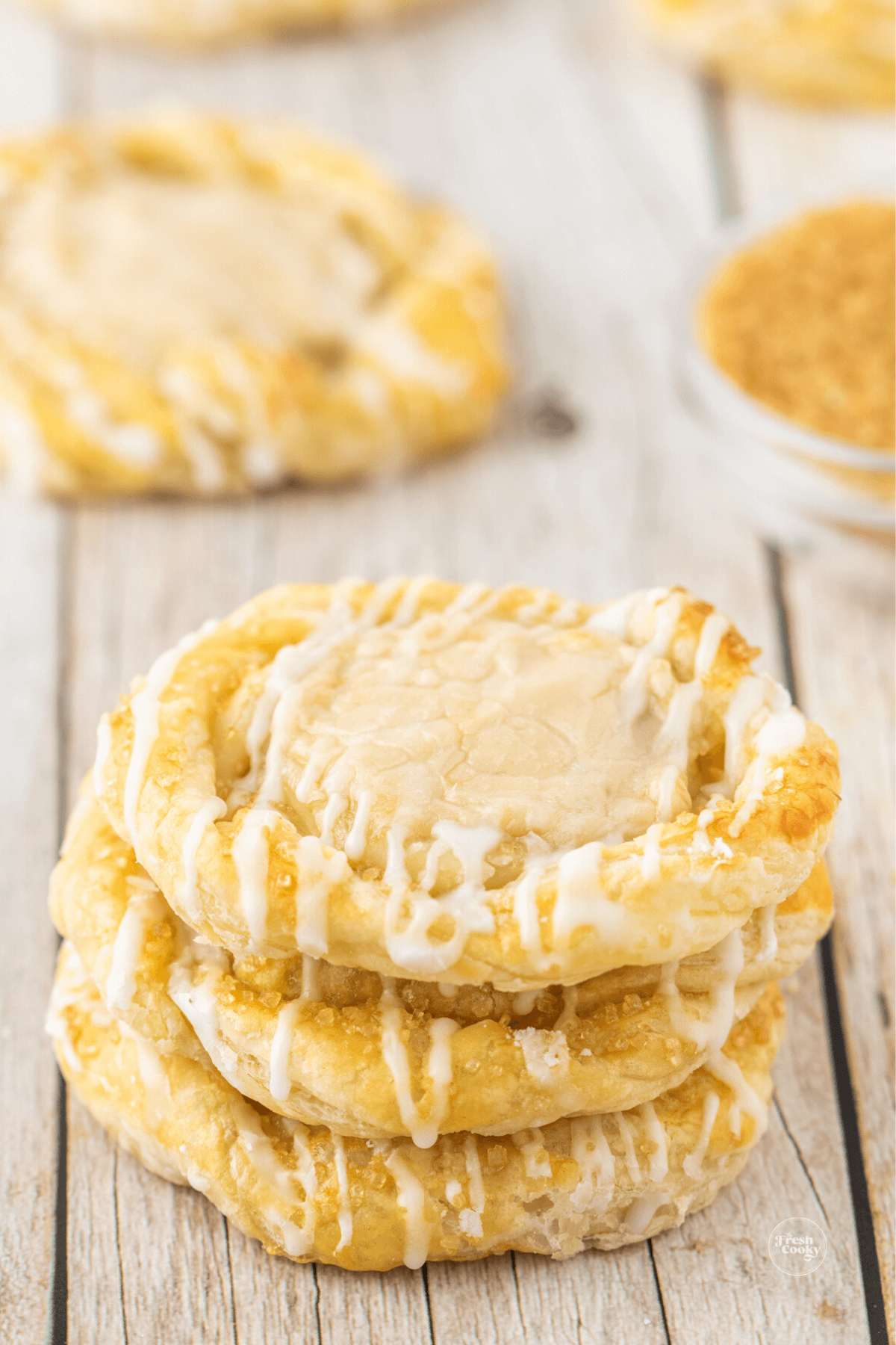 Three stacked cream cheese danish with others in background.