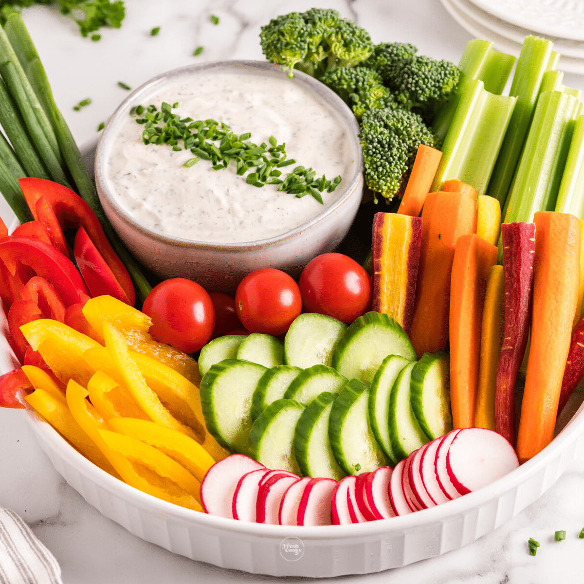 Crudites dip in bowl with larger bowl filled with fresh, crisp veggies.