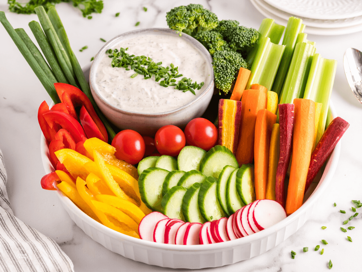 Crudite dip surrounded by bright and crisp veggies.
